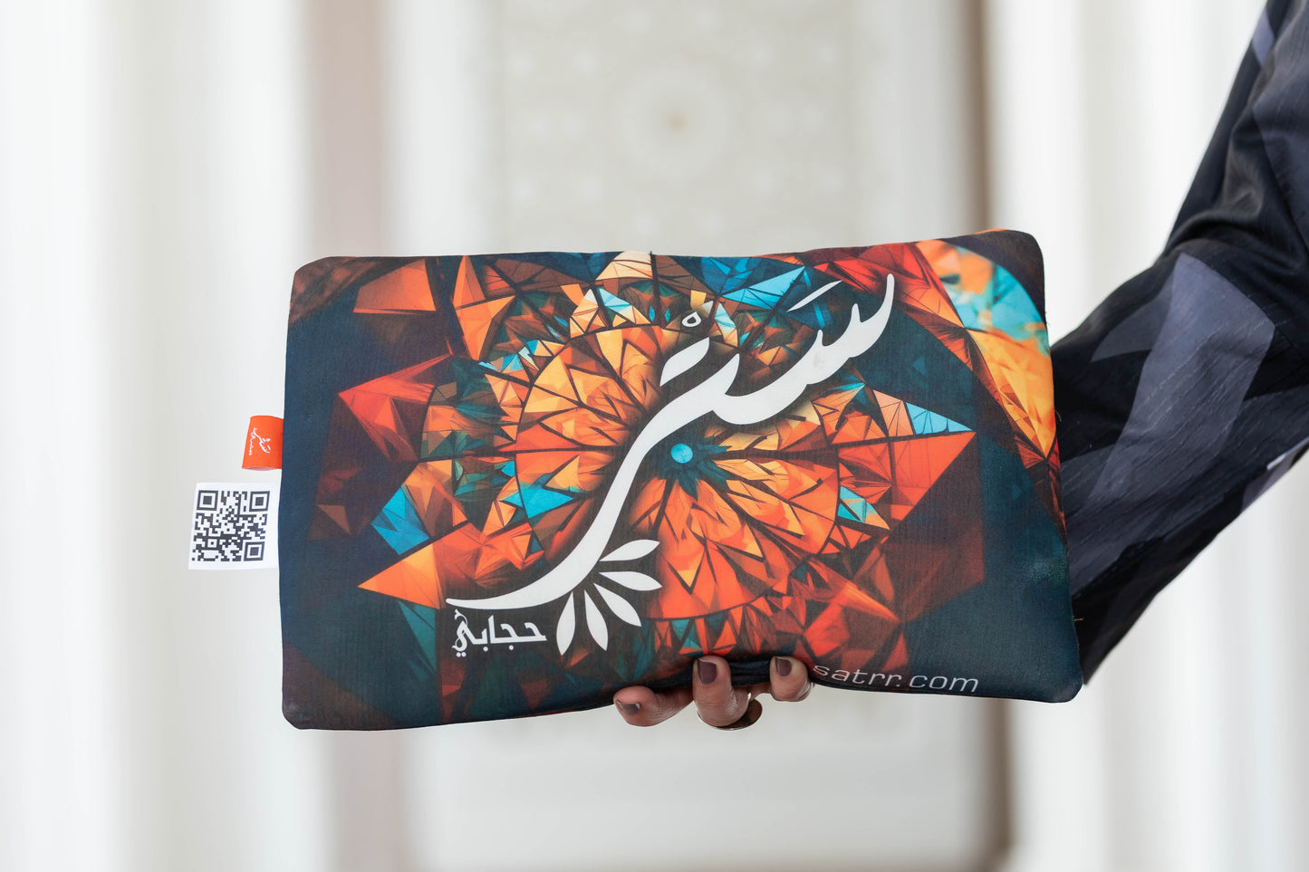 Vibrant abstract clutch bag with colorful geometric design, held in hand against white background