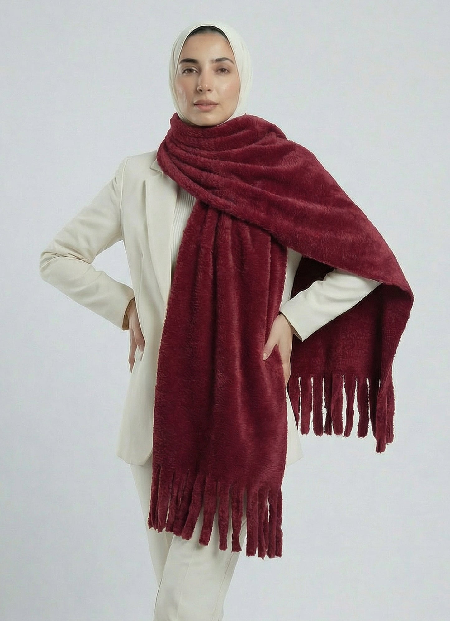 Person wearing a burgundy scarf with tassels on a white background
