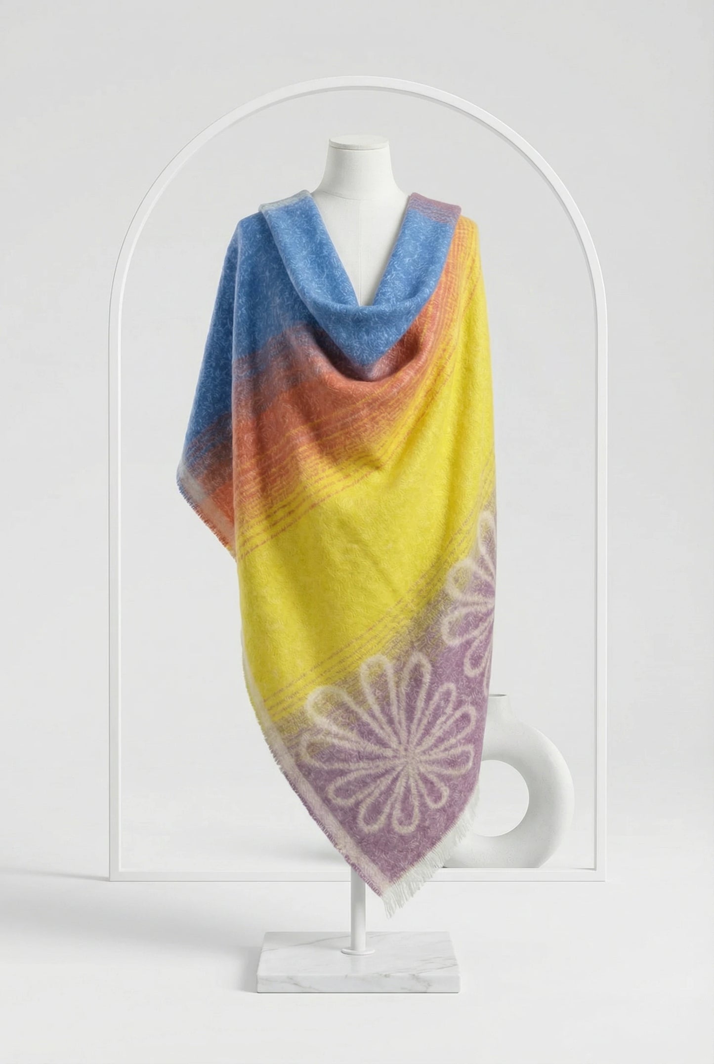 Colorful knitted shawl with a floral pattern on a mannequin against a white background
