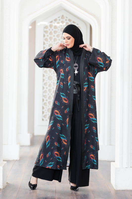 Colorful feather-patterned digital print kimono with long sleeves and a draped silhouette, worn by a person standing in a bright, architecturally detailed setting.