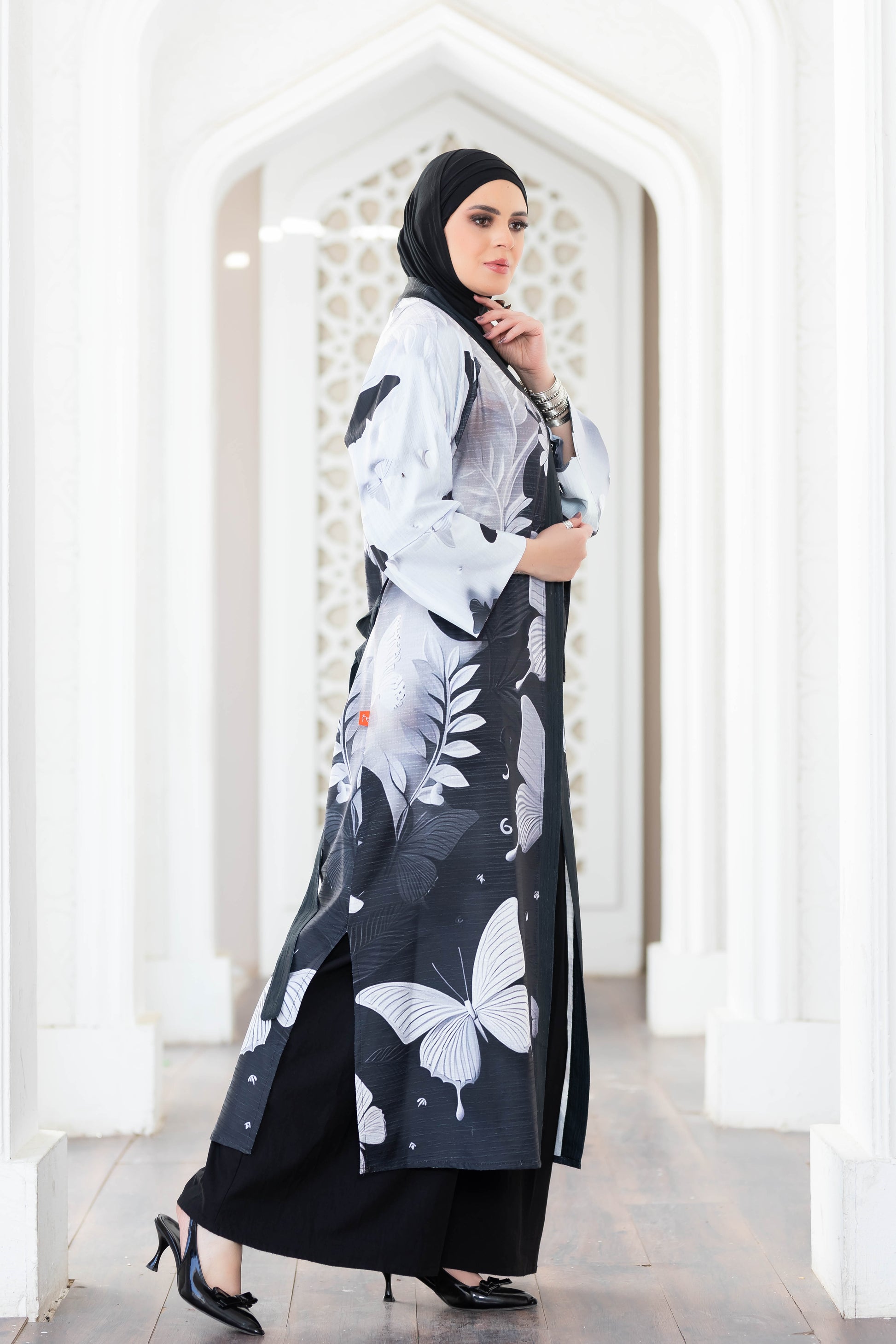 Elegant digital print kimono with butterfly motif and flared sleeves, modeled in an architectural setting.