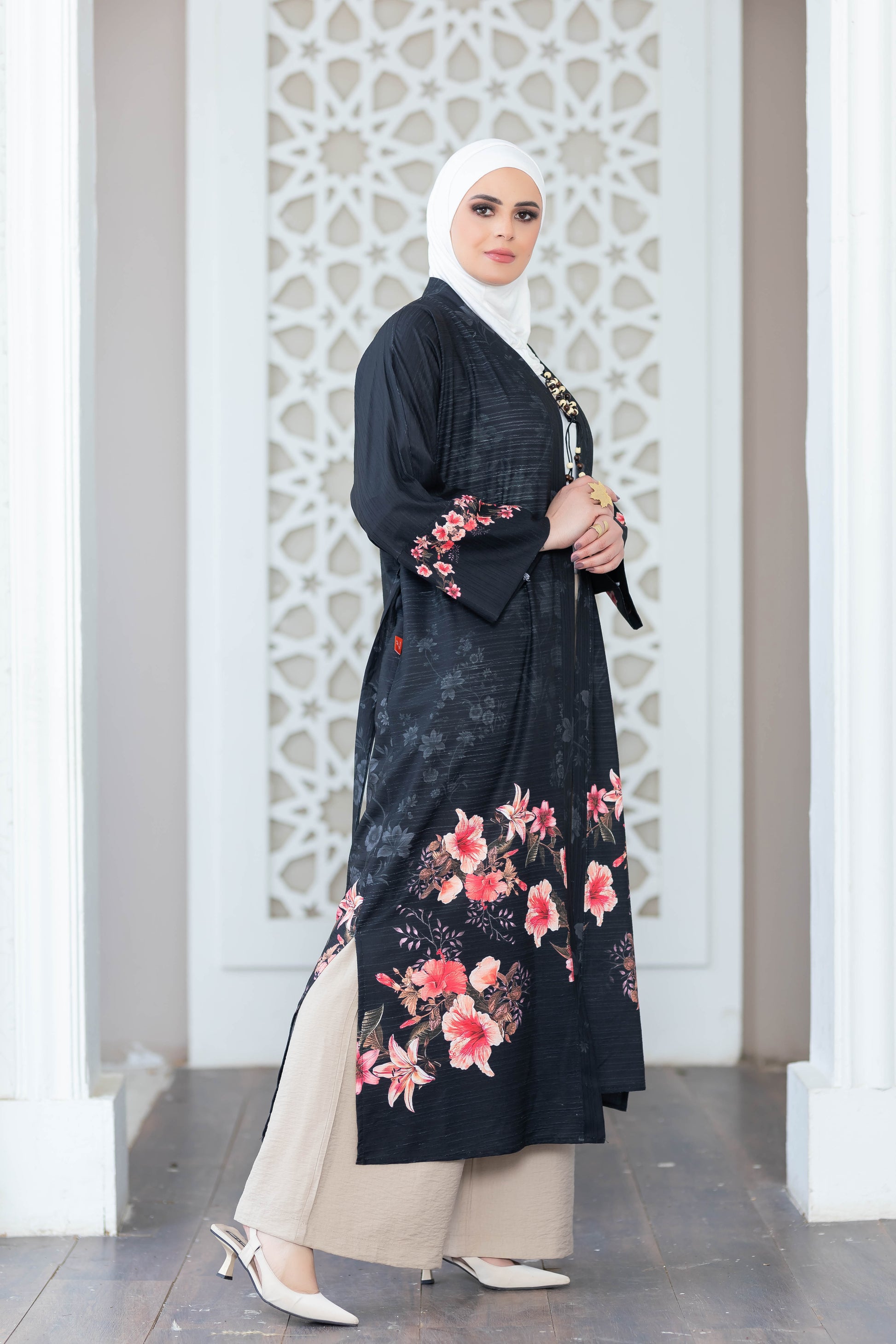 Elegant floral kimono with flowing black fabric, delicate pink flowers, and a modest hijab for a graceful Islamic fashion look.
