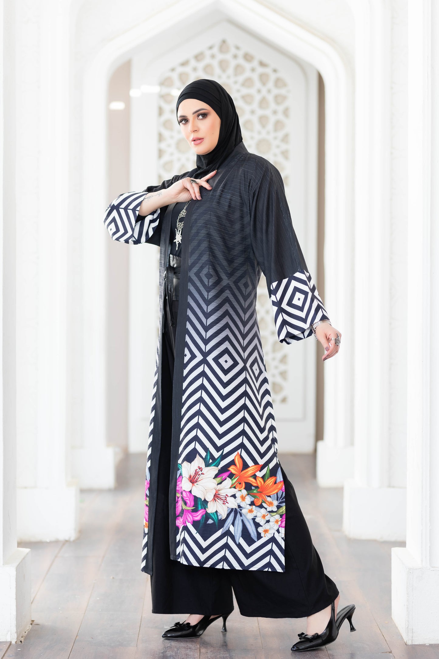 Elegant black and white patterned digital print kimono with flowing sleeves, displayed against a white architectural background.