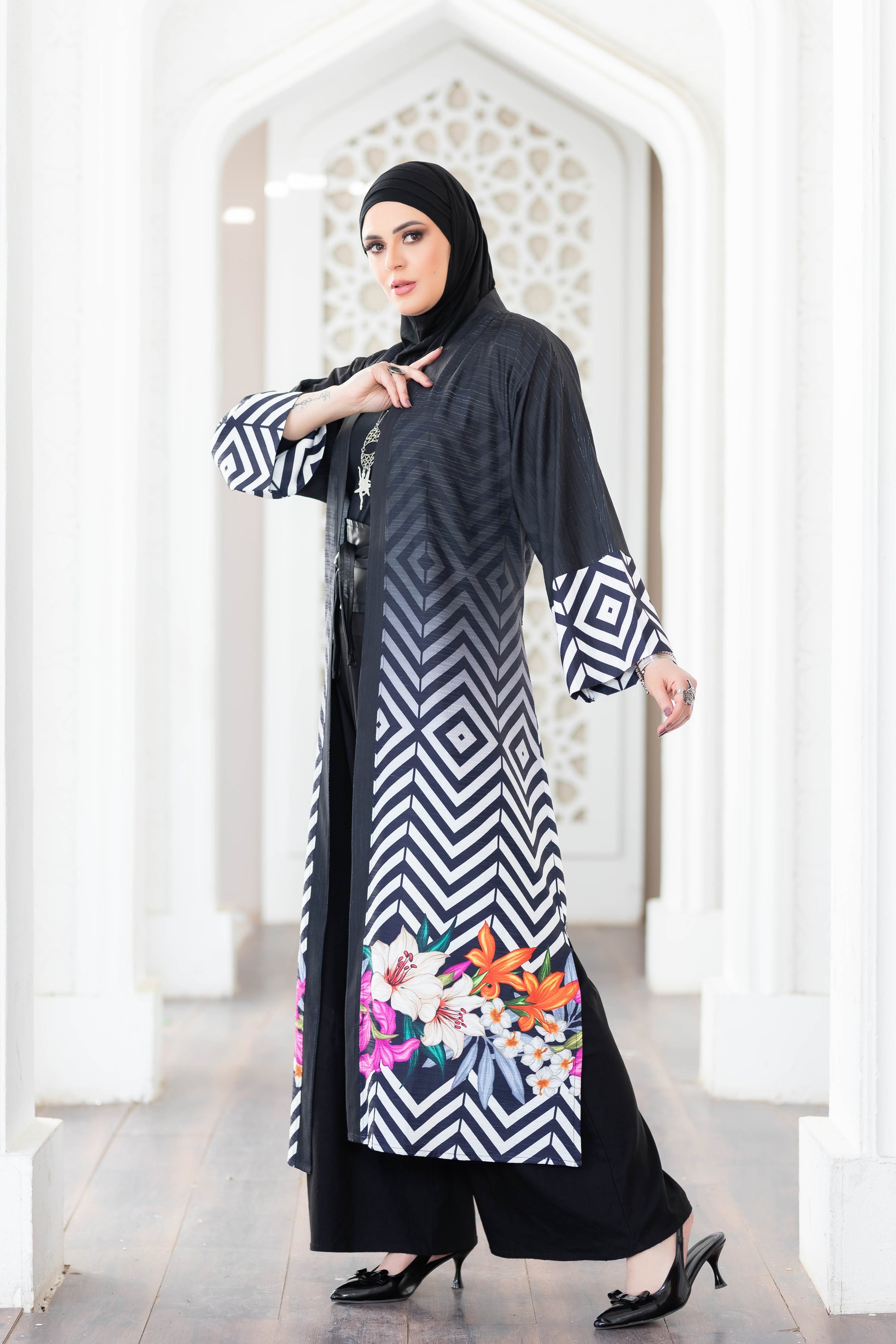 Elegant black and white patterned digital print kimono with flowing sleeves, displayed against a white architectural background.