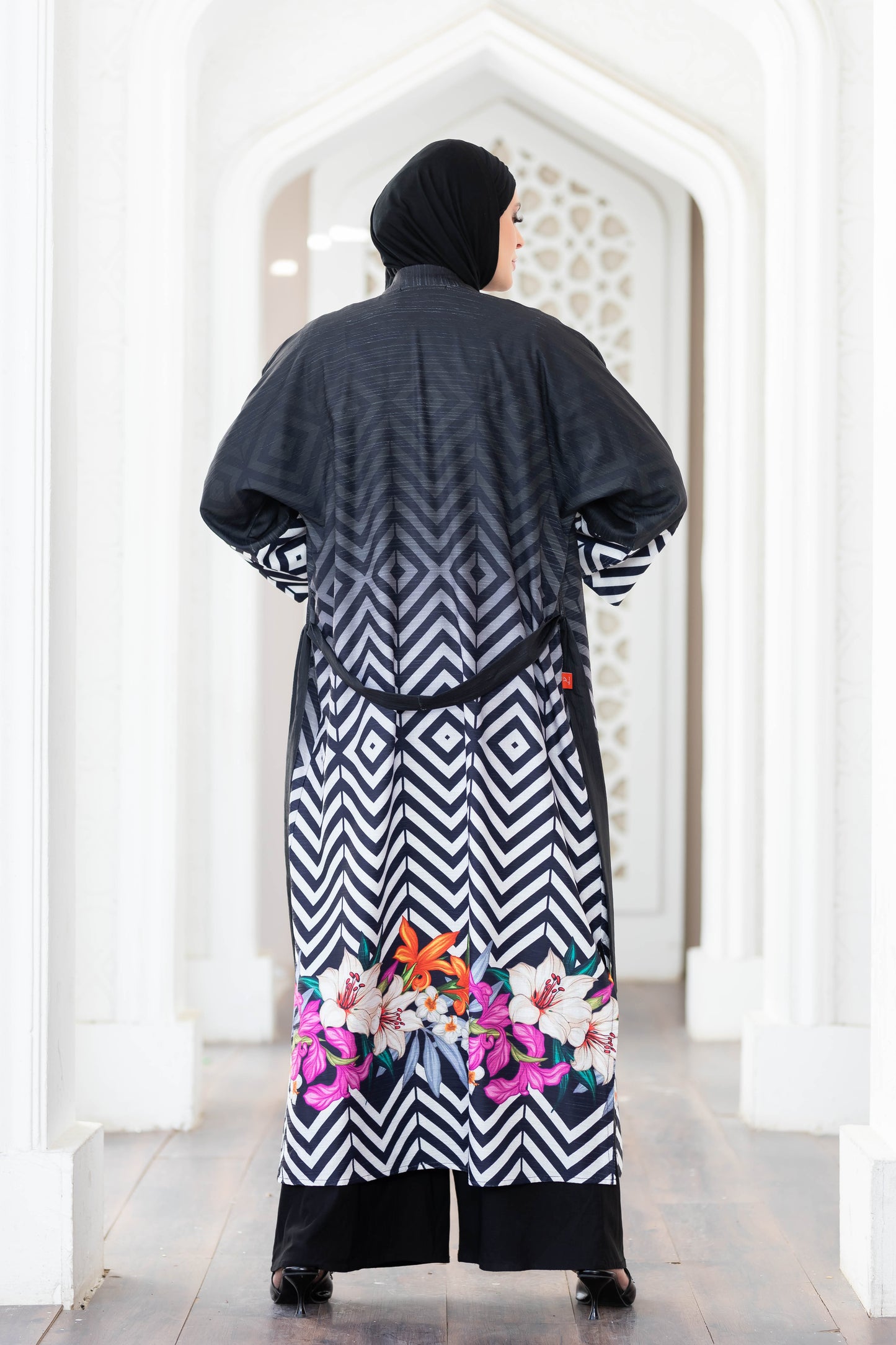 Elegant black and white digital print kimono with vibrant floral accents, showcased in a sleek, modern setting.