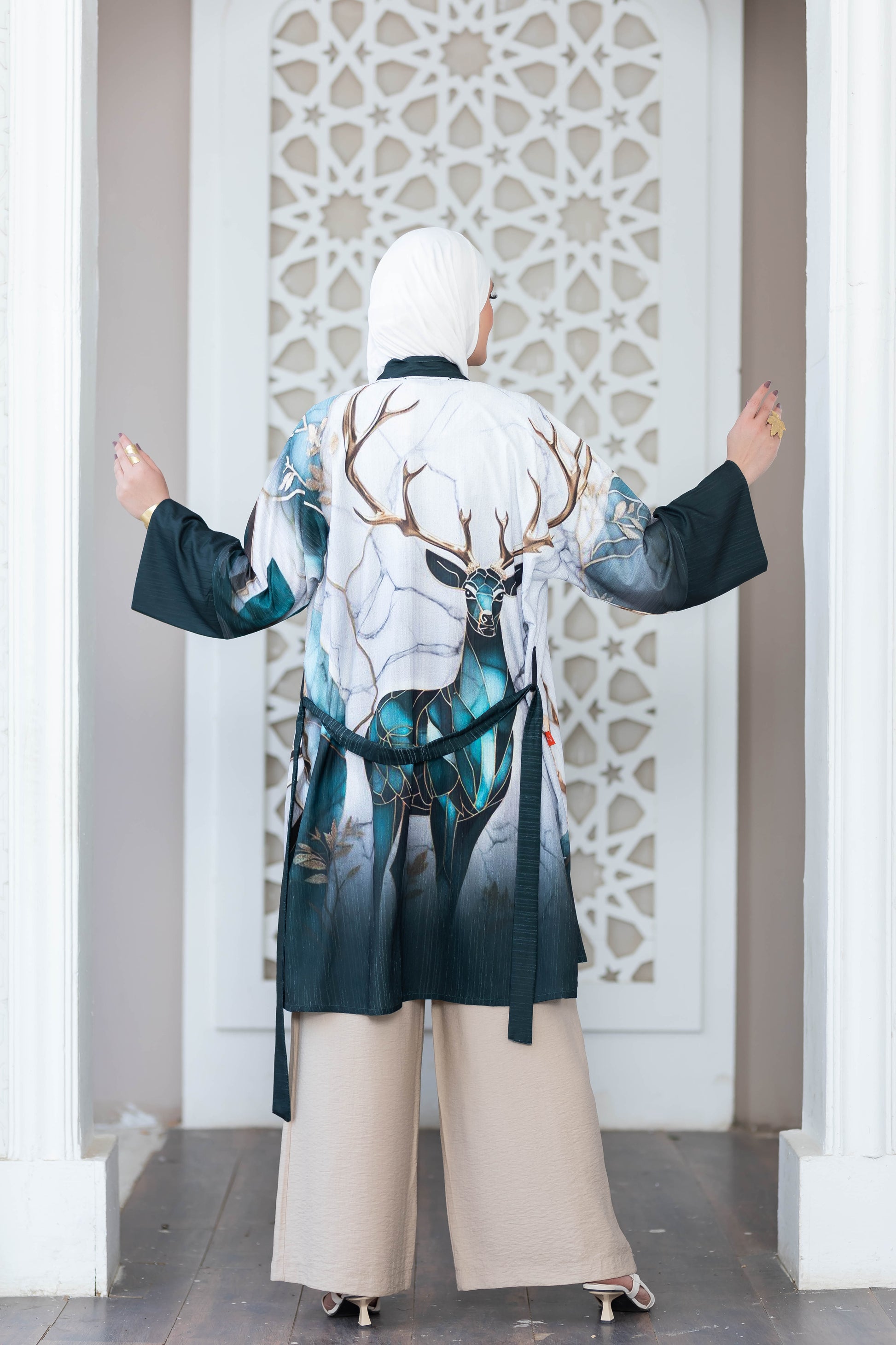 Elegant deer print kimono in a serene, architectural setting. Detailed digital artwork showcases a majestic deer motif against a white ornamental backdrop.