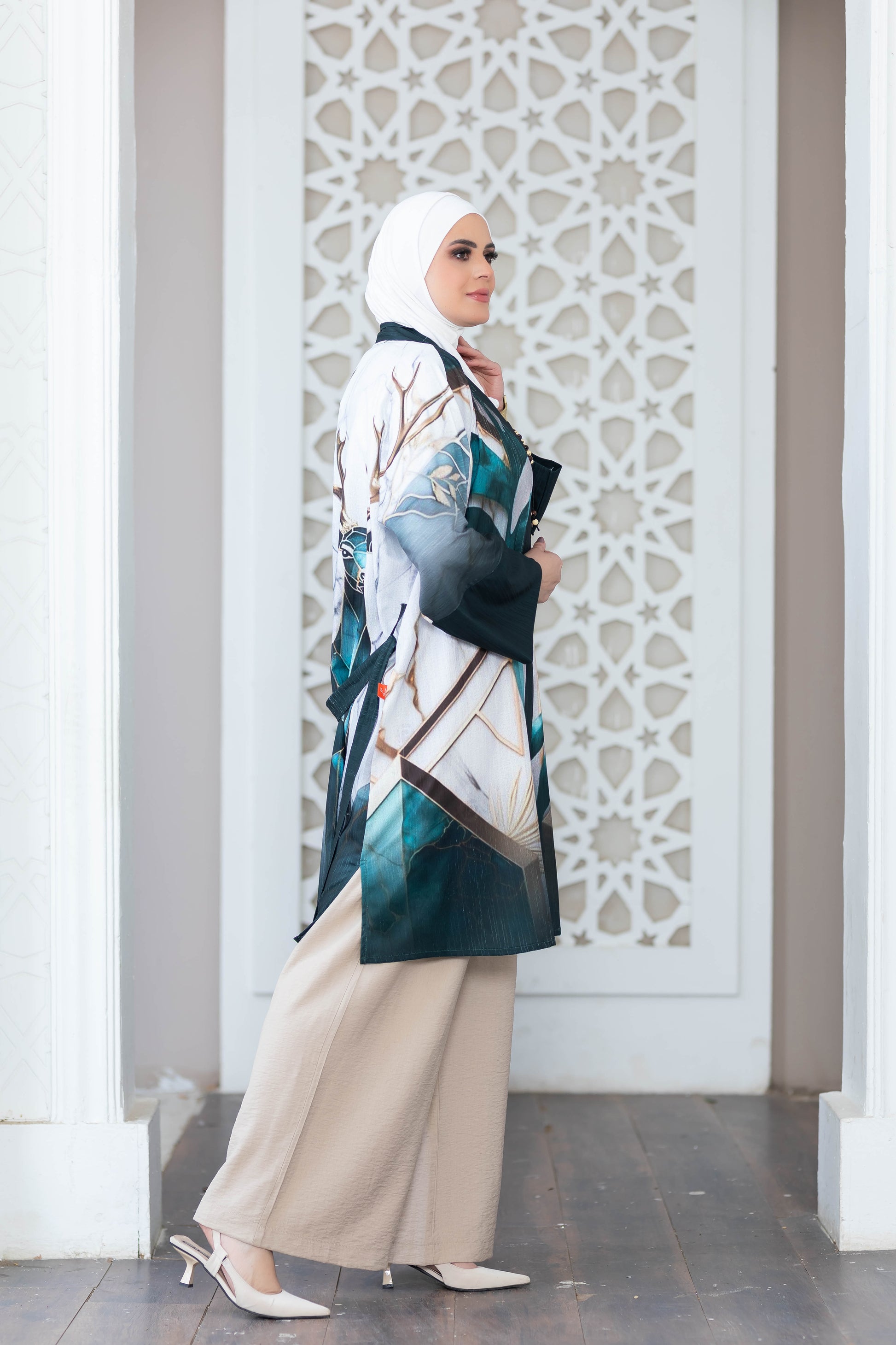 Elegant digital print kimono with intricate floral pattern, worn by a woman with a hijab, standing in a minimalist architectural setting.