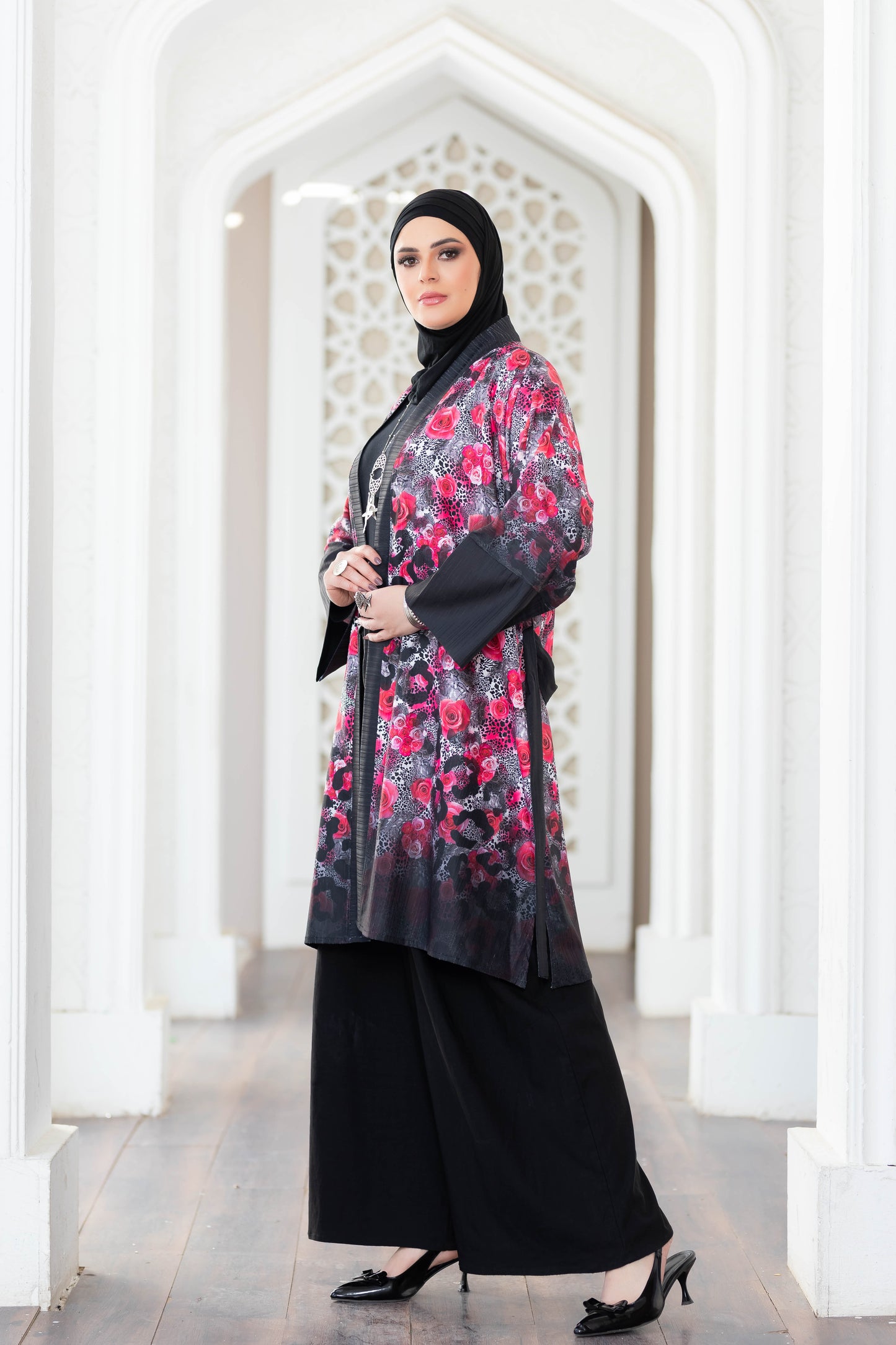 Stylish floral printed kimono, vibrant colors, modest fashion, woman in hijab, contemporary Islamic attire, architectural background.