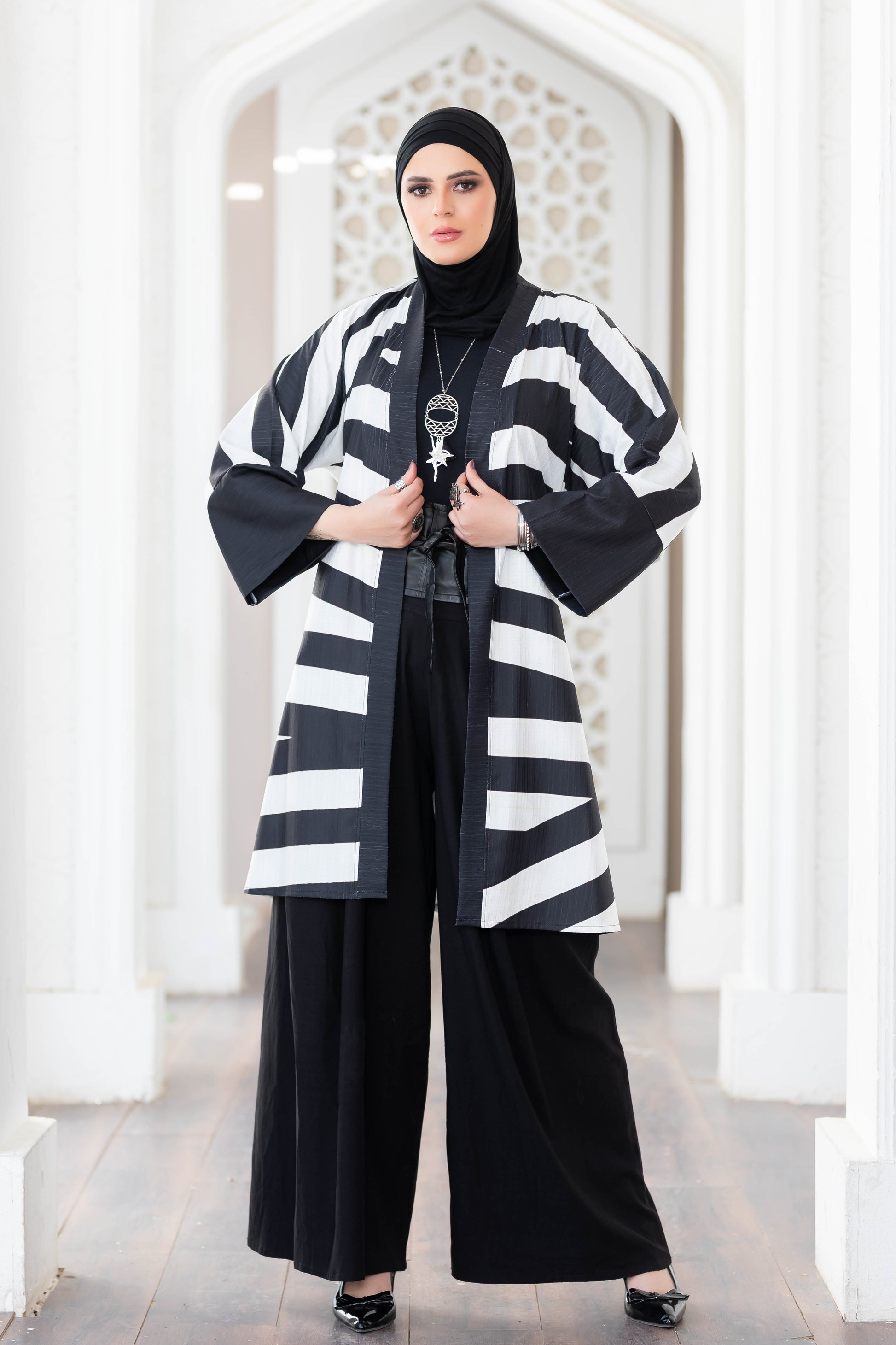 Patterned kimono with monochrome design, worn by a woman in traditional Islamic attire standing in an architectural setting.