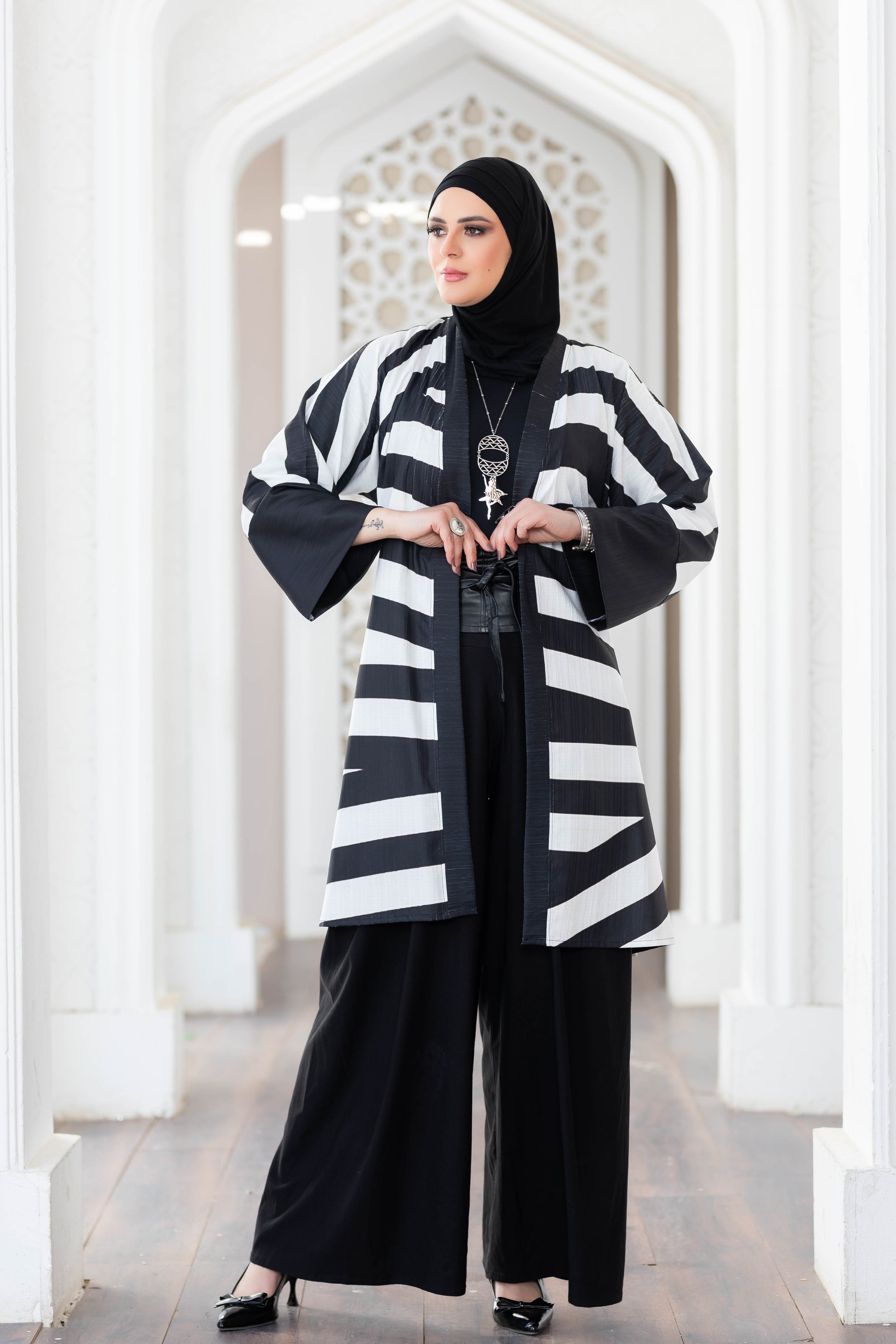Elegant striped kimono with flared sleeves, worn over a black outfit, showcasing a stylish and modest fashion choice.