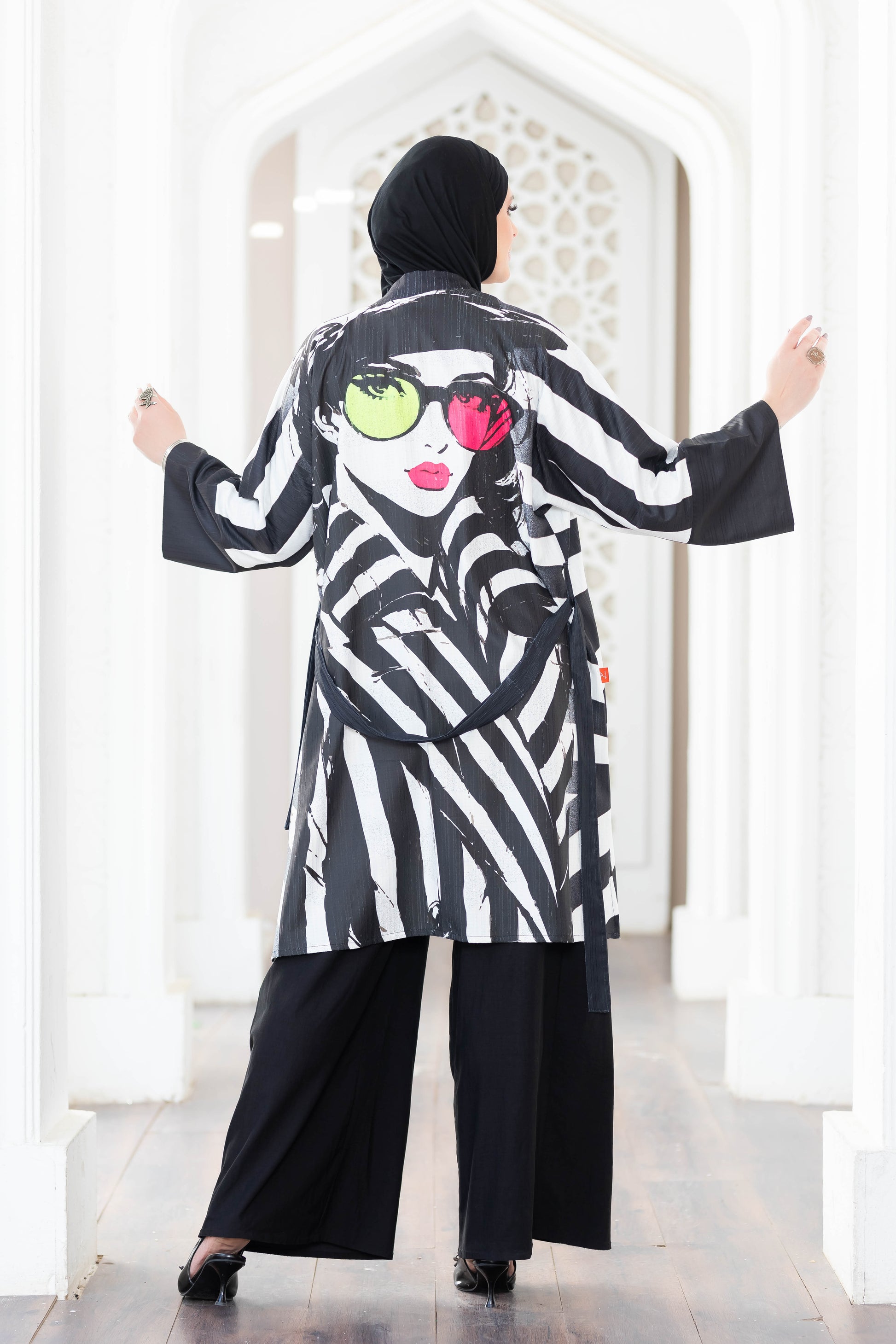 Stylish black and white striped kimono with vibrant pattern, worn by a female model in a modern setting.