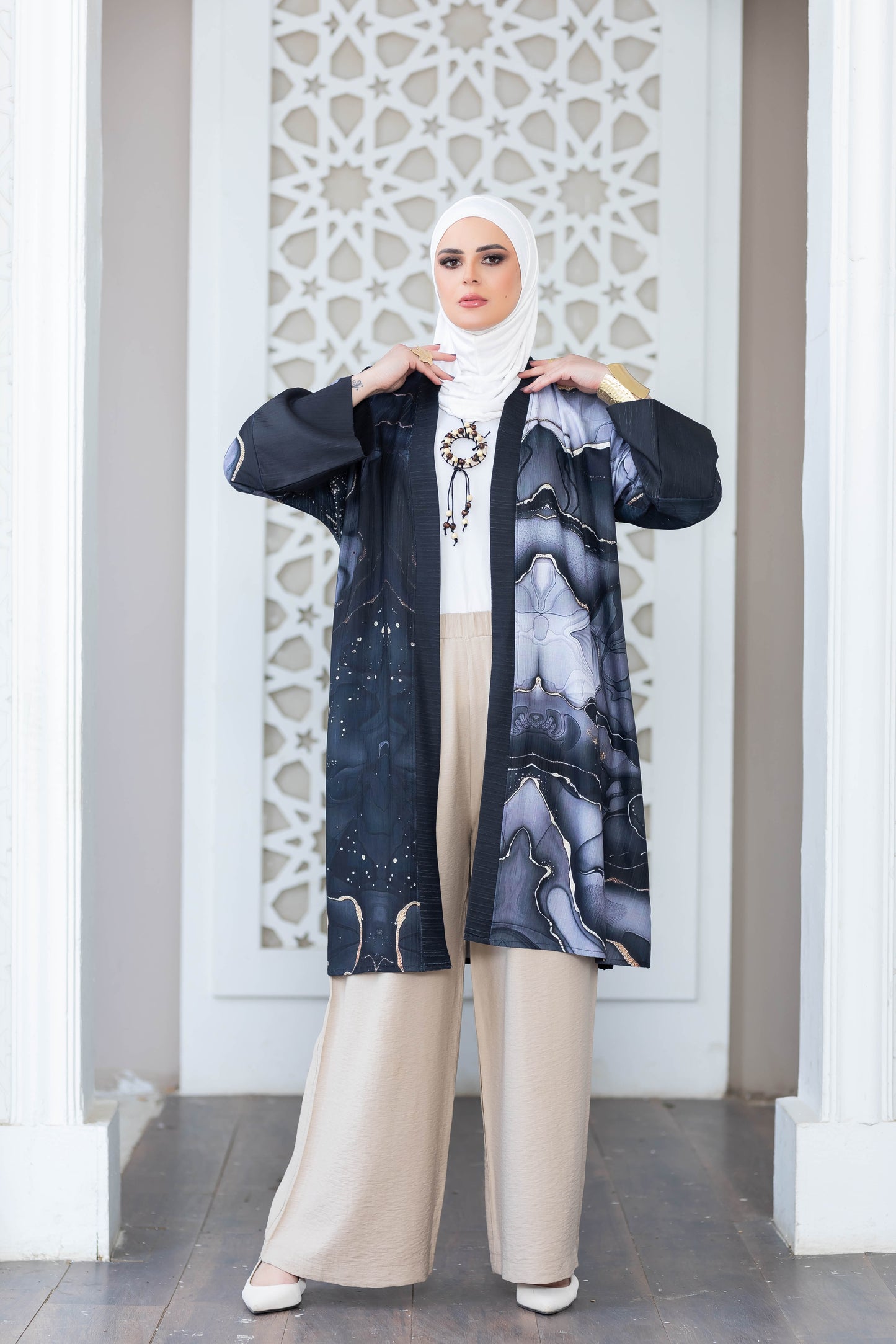 Elegant digital print kimono with abstract floral patterns, worn over a light-colored outfit, showcased in front of an intricate architectural backdrop.