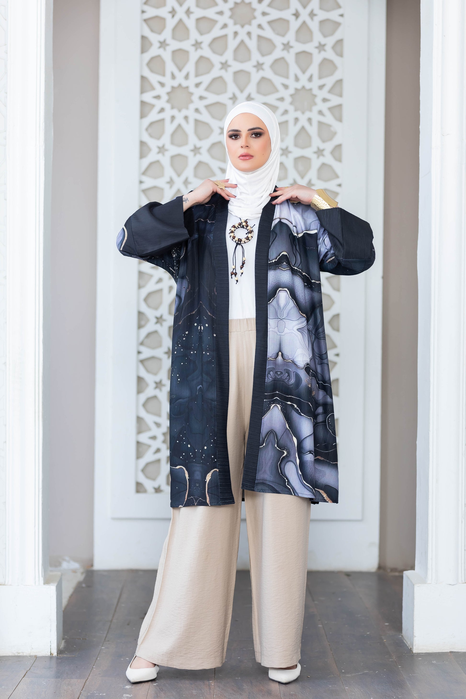 Elegant digital print kimono with abstract floral patterns, worn over a light-colored outfit, showcased in front of an intricate architectural backdrop.
