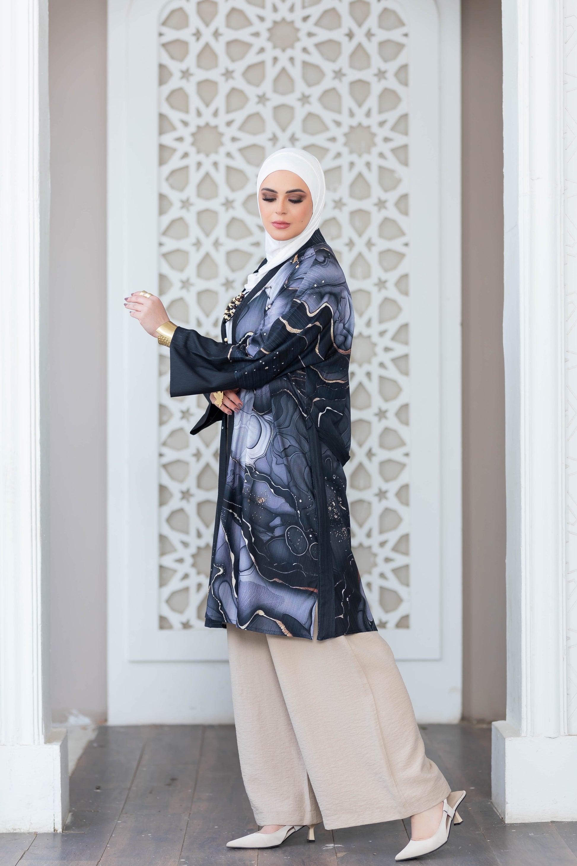 Elegant Islamic fashion: Patterned long kimono with hijab and modest ensemble, set against a decorative architectural backdrop.