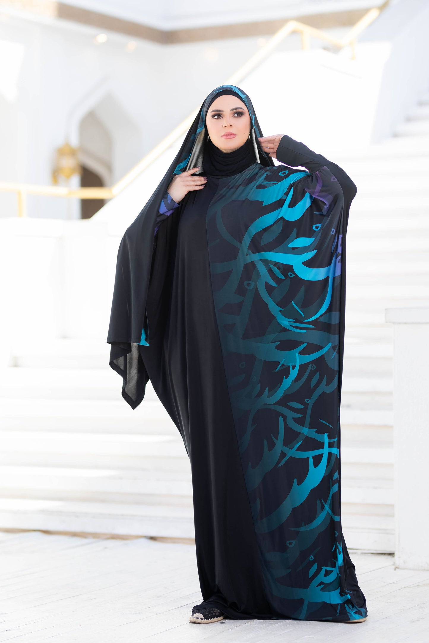 Modest Isdal 777177 - Traditional Islamic woman's cloak with abstract floral design in blue and green tones, worn over a black base.