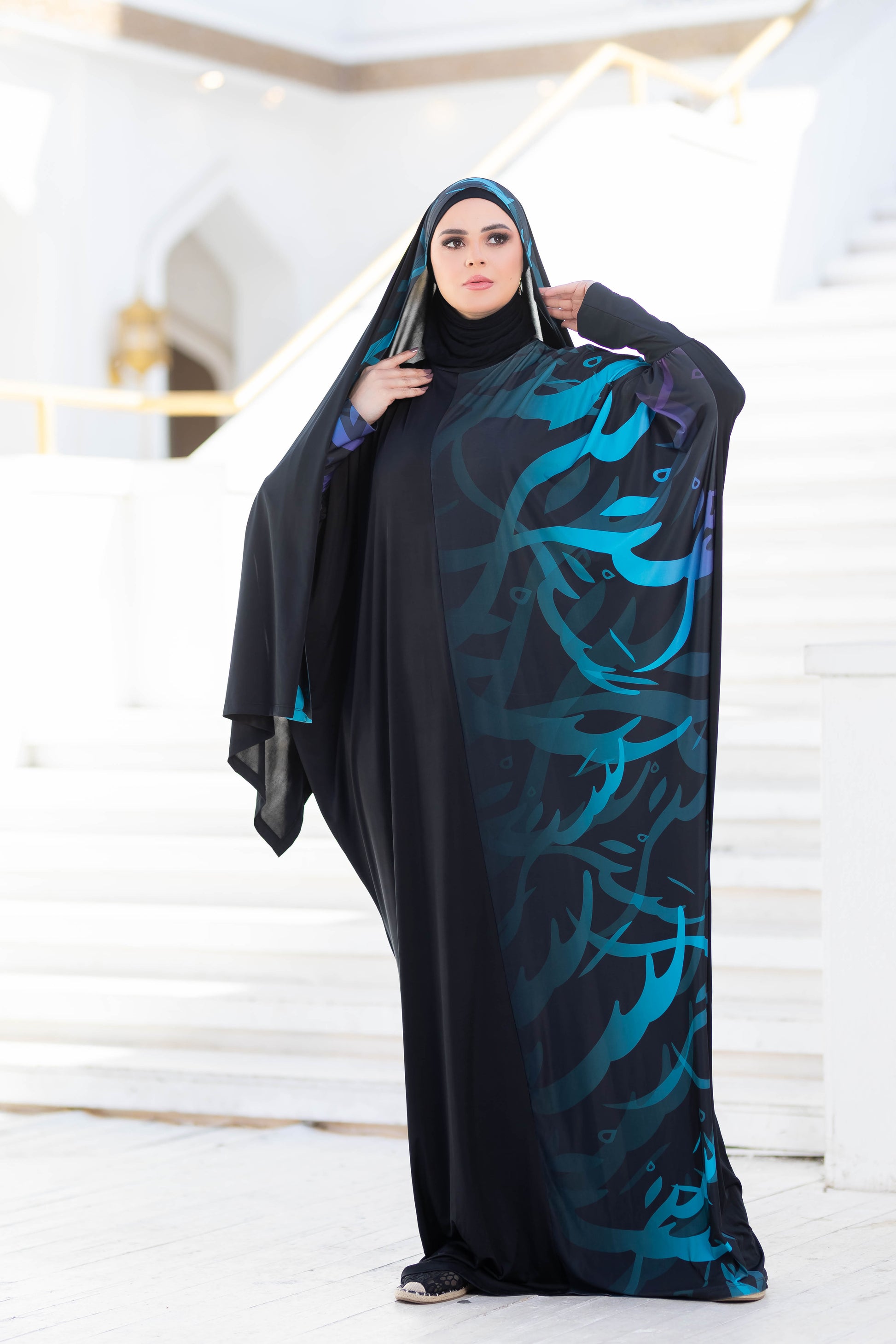 Modest Isdal 777177 - Traditional Islamic woman's cloak with abstract floral design in blue and green tones, worn over a black base.