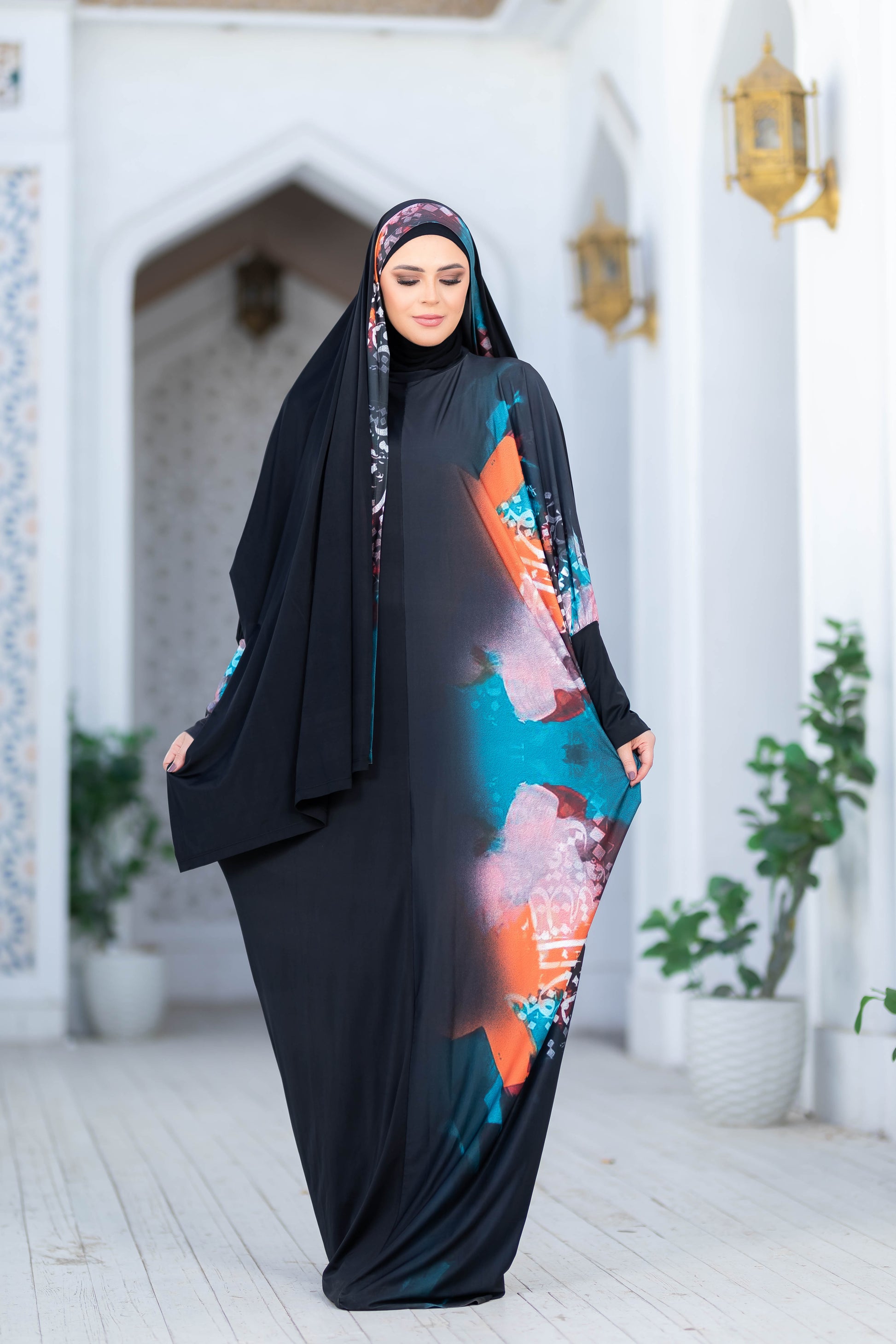 Modest Isdal 777179 elegant abaya with floral print and long sleeves, worn by a woman in a traditional Islamic setting.