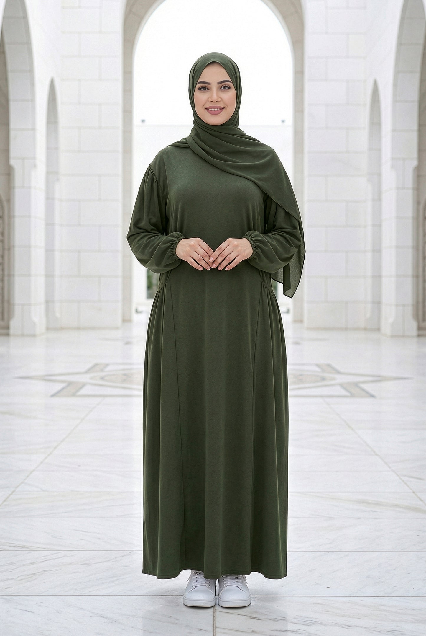 Model wearing a dark olive Royale Isdal with full modest coverage in an outdoor architectural courtyard.