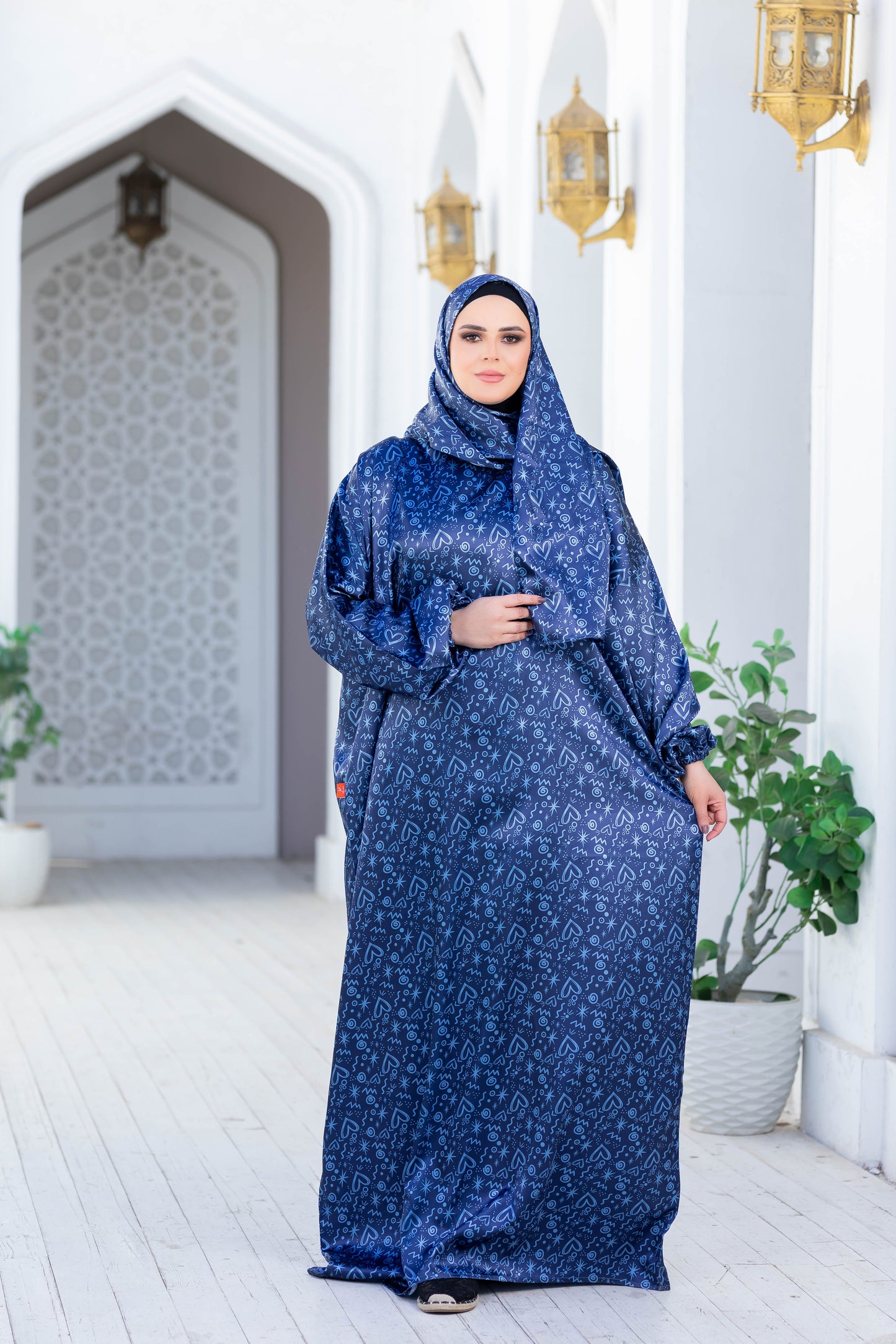 Modest Isdal 777187: Elegant blue patterned modest dress with long sleeves and hijab, displayed in an Islamic architectural setting.