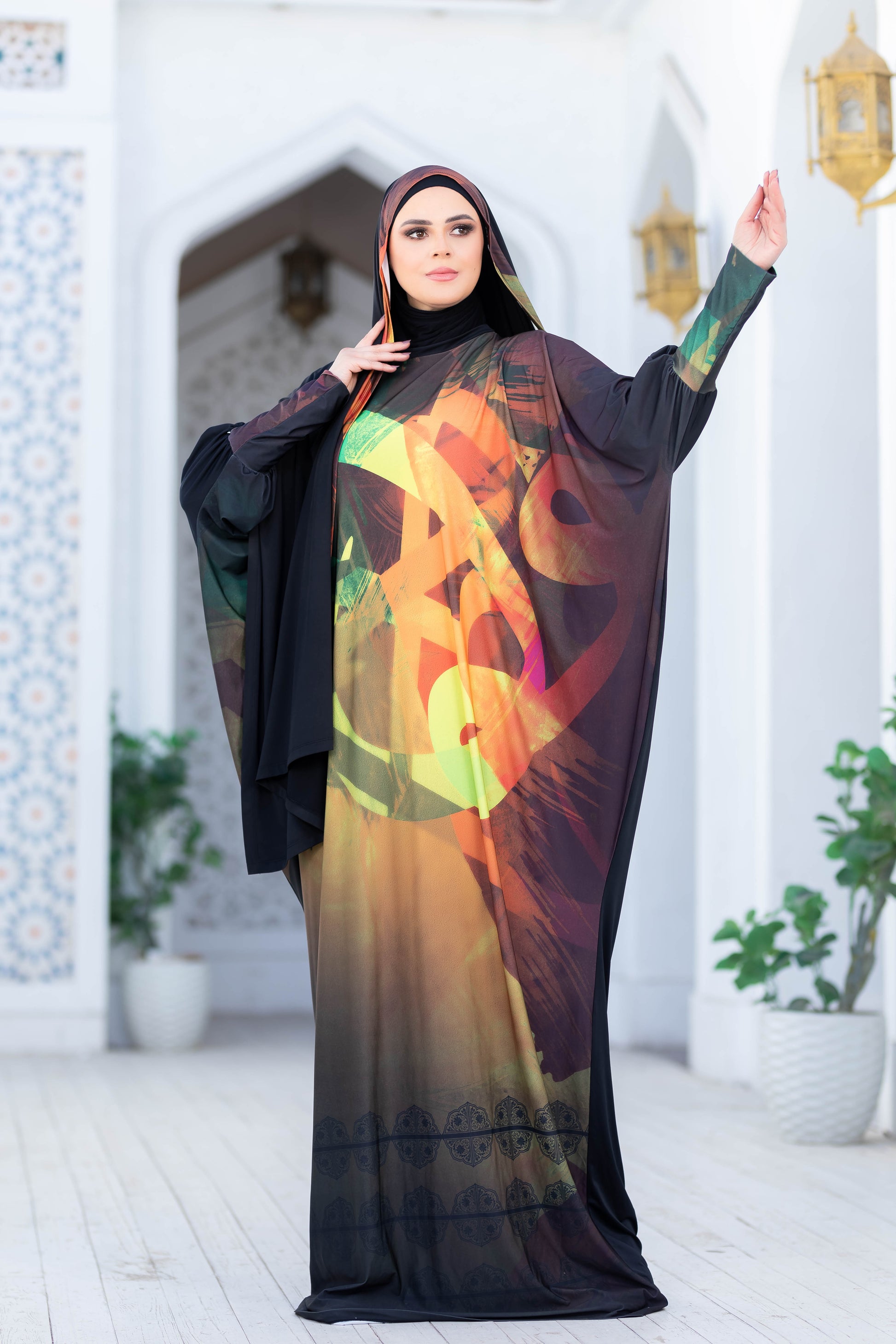 Modest Isdal 77717: Vibrant, patterned maxi dress with black hijab, showcased in front of a traditional architectural setting.