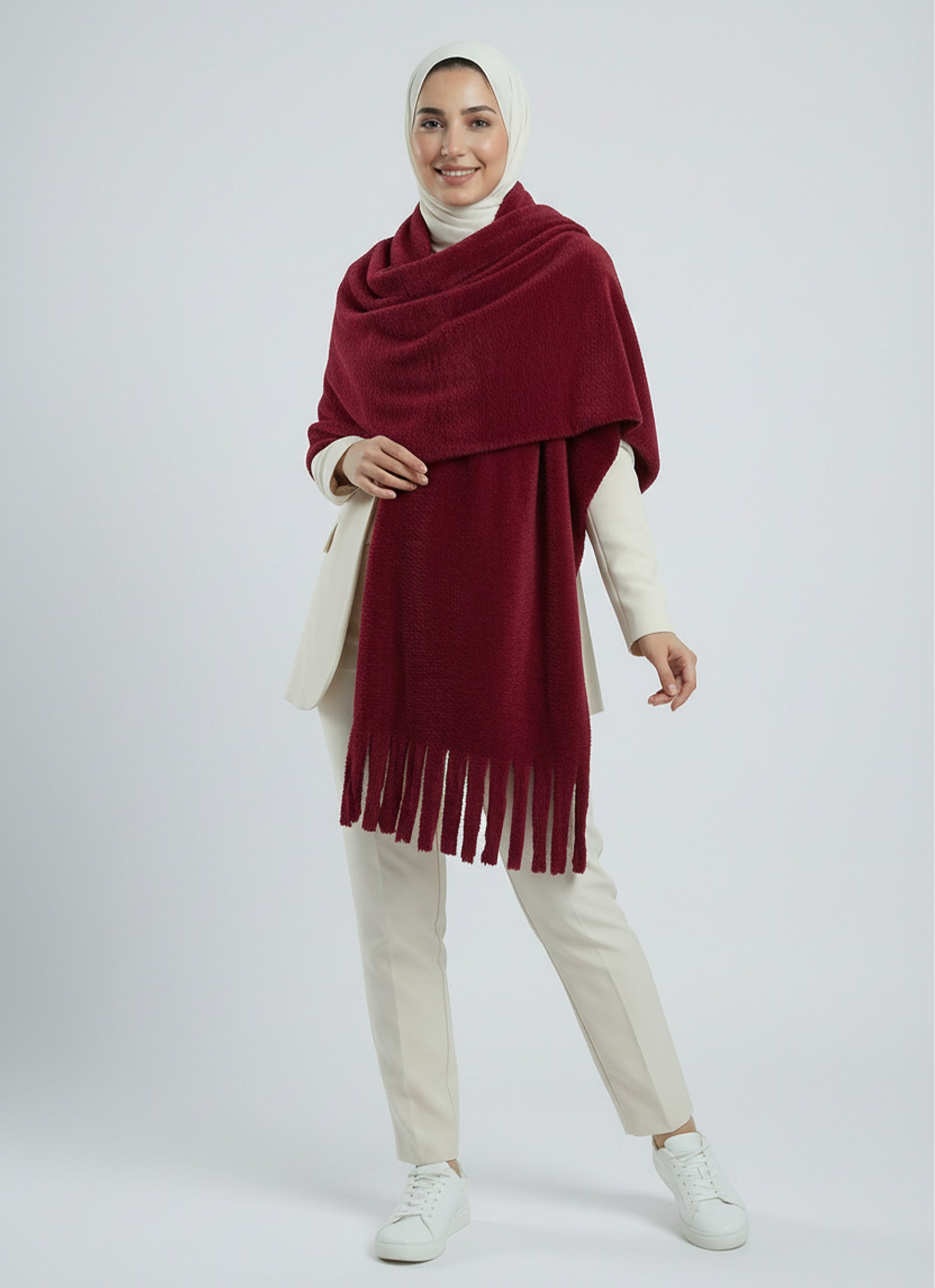 Woman wearing a red scarf with fringe on a white background
