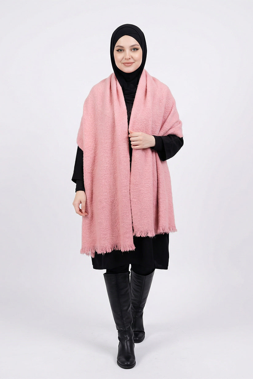 Person wearing a pink scarf, black hijab, black top, and black pants on a white background