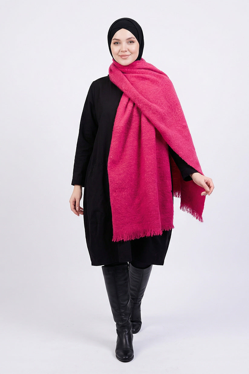 Woman wearing a bright pink scarf, black outfit, and black hijab on a white background