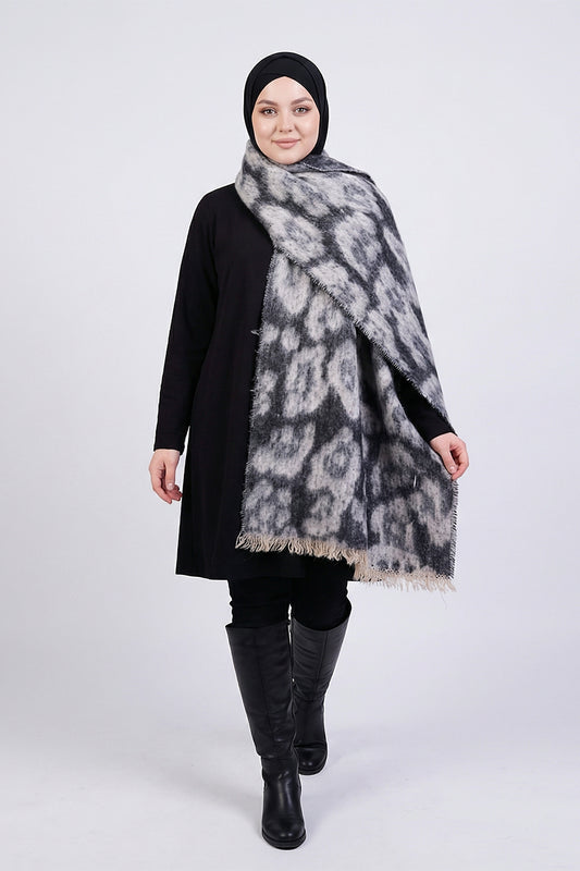 Woman wearing a black hijab, black outfit, and a patterned scarf on a white background