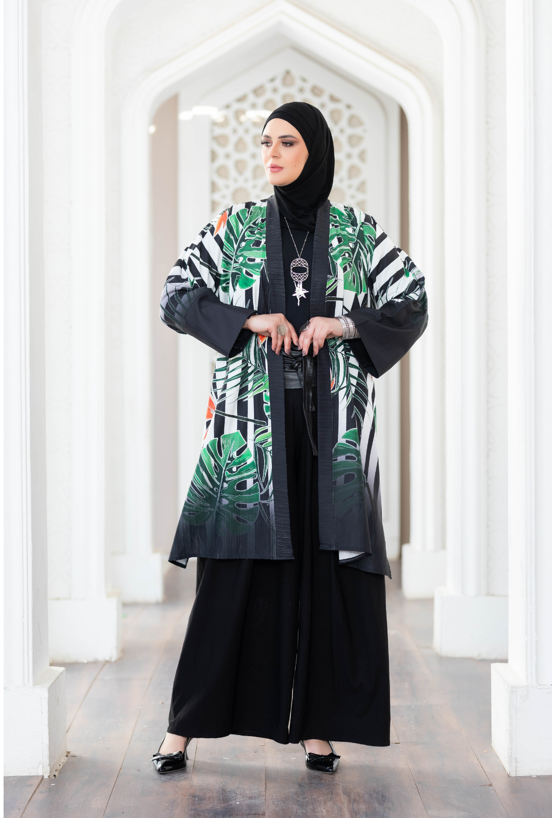 Elegant botanical print kimono with flowing sleeves, worn by a woman in a traditional Islamic headscarf, standing in a decorative archway.