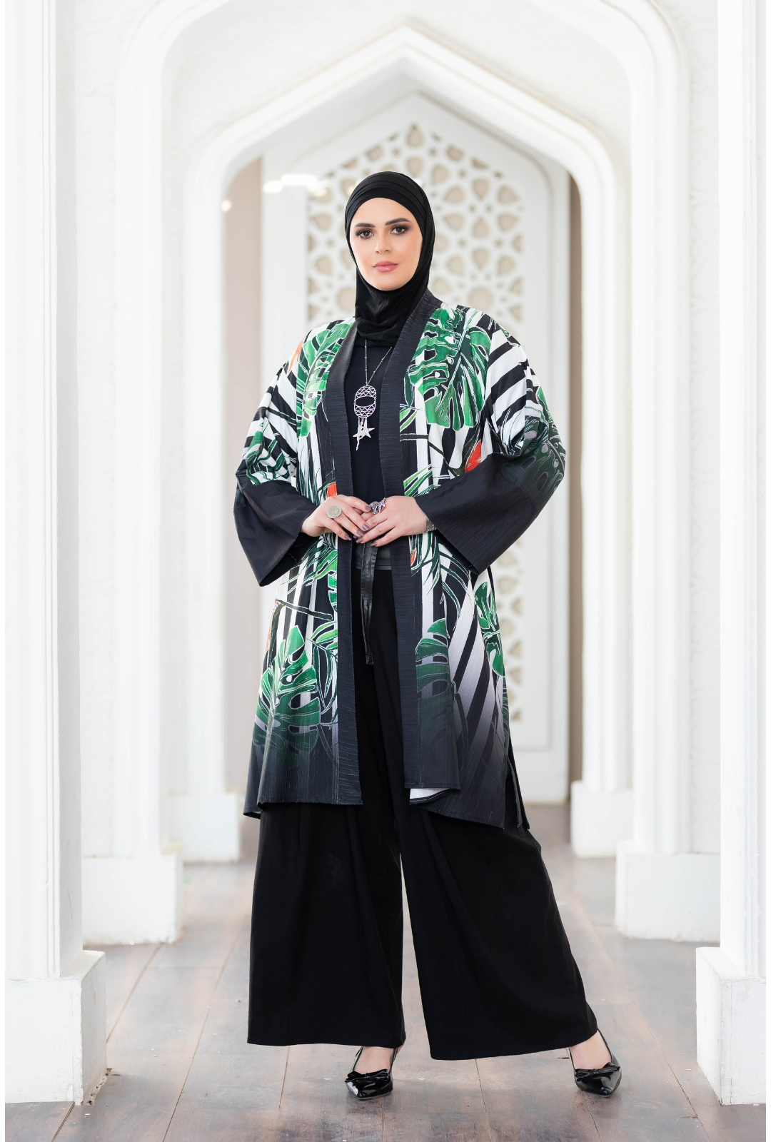 Green tropical print short kimono styled with black abaya in elegant architectural setting