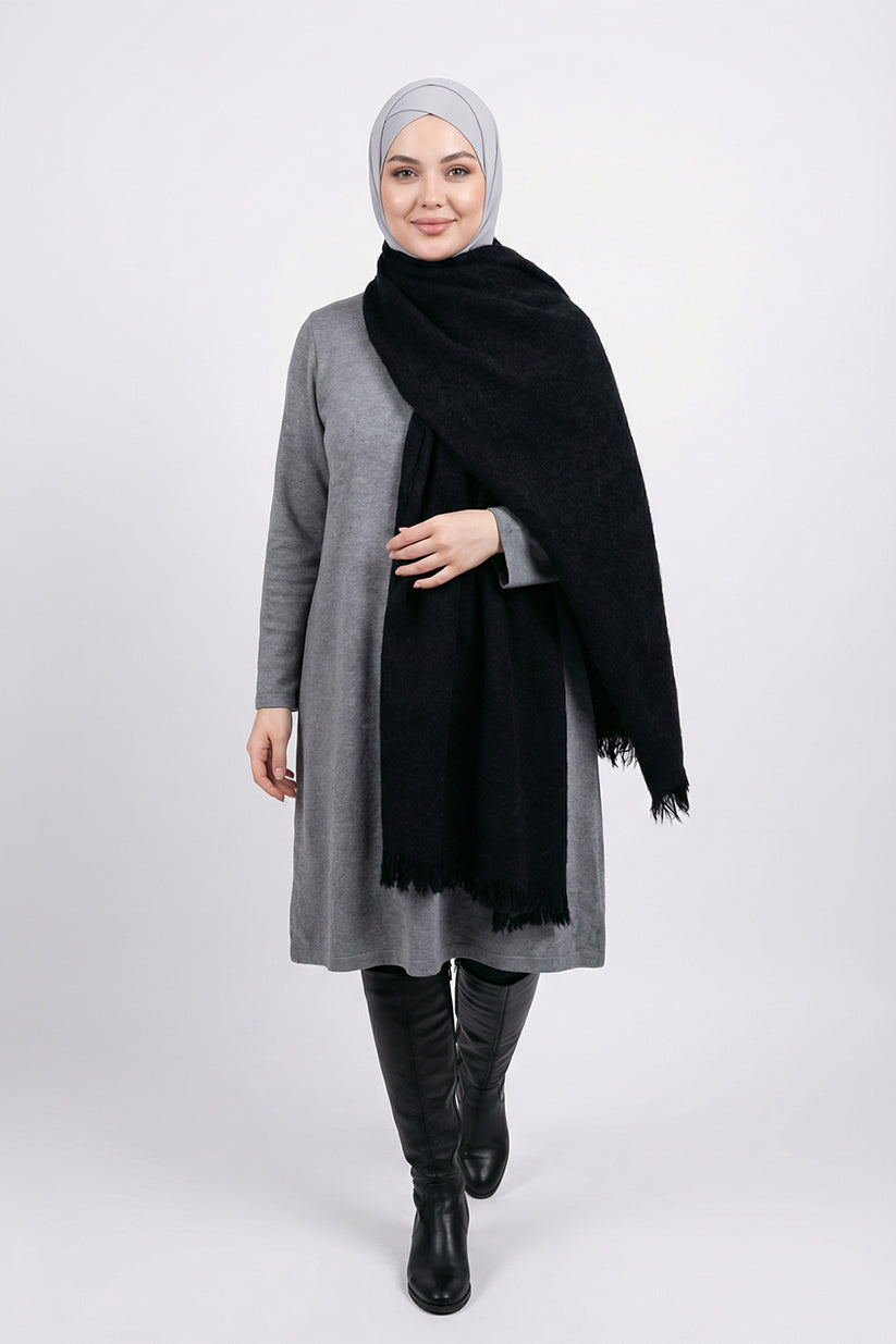 Woman wearing a gray coat, black scarf, and black boots on a white background