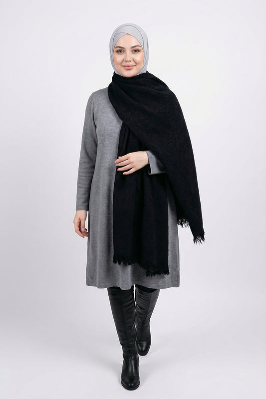 Woman wearing a gray coat, black scarf, and black boots on a white background