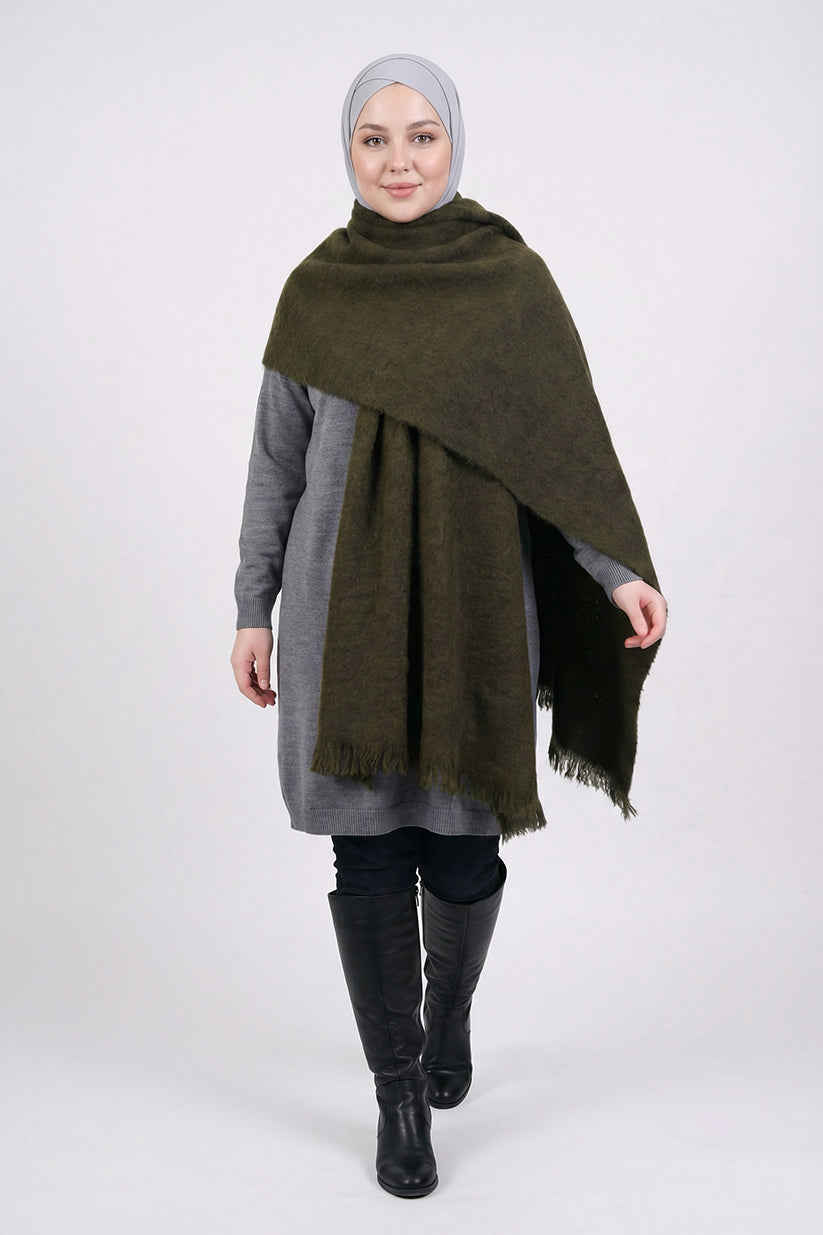 Woman wearing a green shawl over a gray outfit on a white background