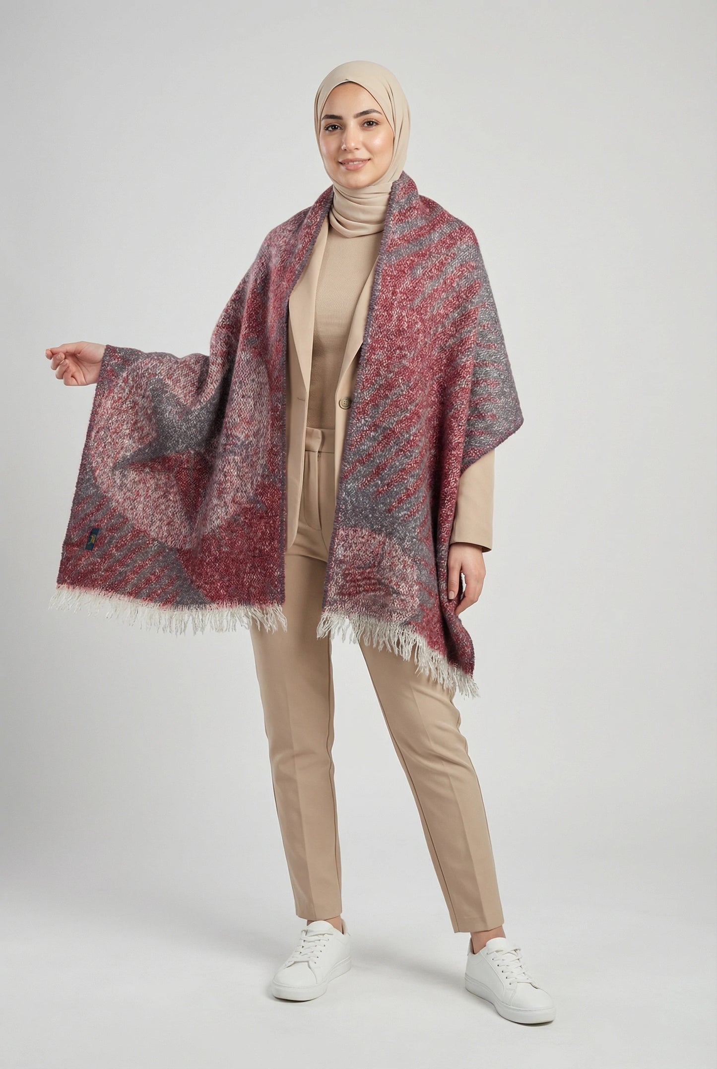 Woman wearing a patterned shawl over a beige outfit on a white background