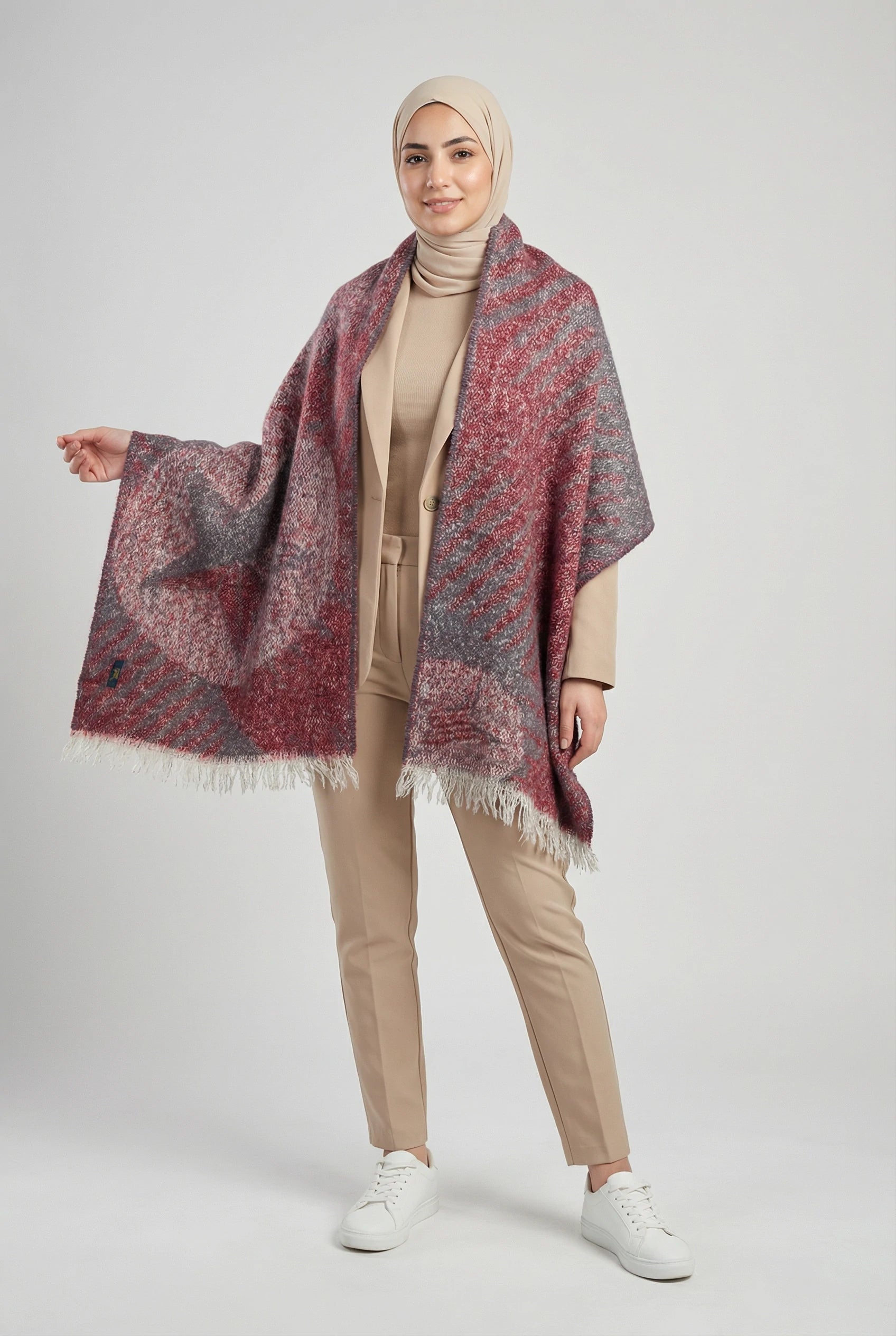 Woman wearing a patterned shawl over a beige outfit on a white background
