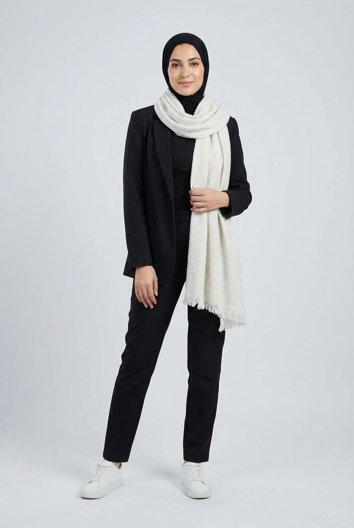 Person wearing a black outfit with a white scarf on a white background