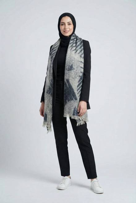 Person wearing a black outfit with a patterned scarf on a white background