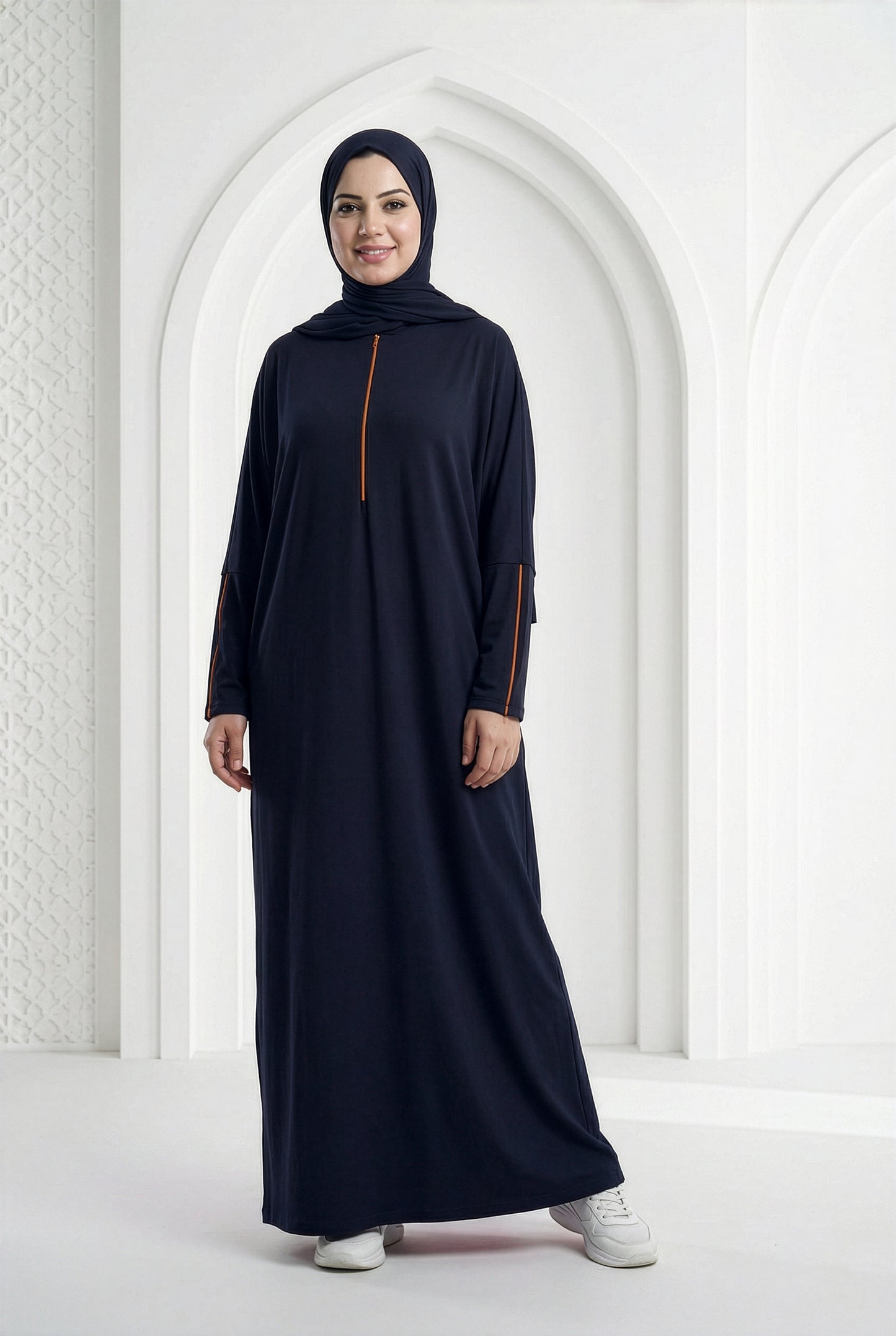 Model wearing a deep navy Oumra Isdal with front and sleeve embroidery, modest flowing fit, standing in an elegant indoor archway