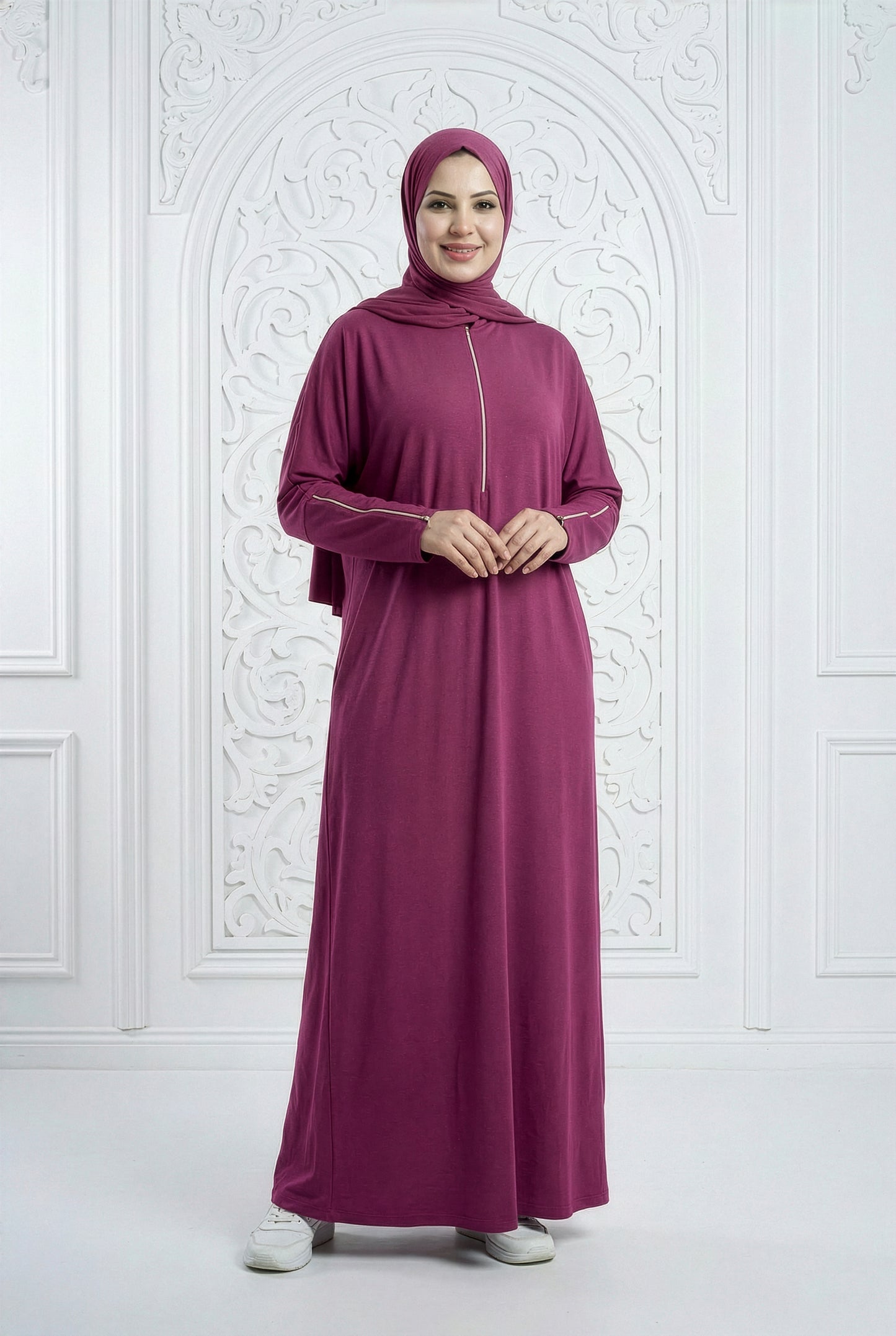 Model wearing a dark fuchsia Oumra Isdal with embroidered details and modest flowing design, standing in an elegant indoor backdrop