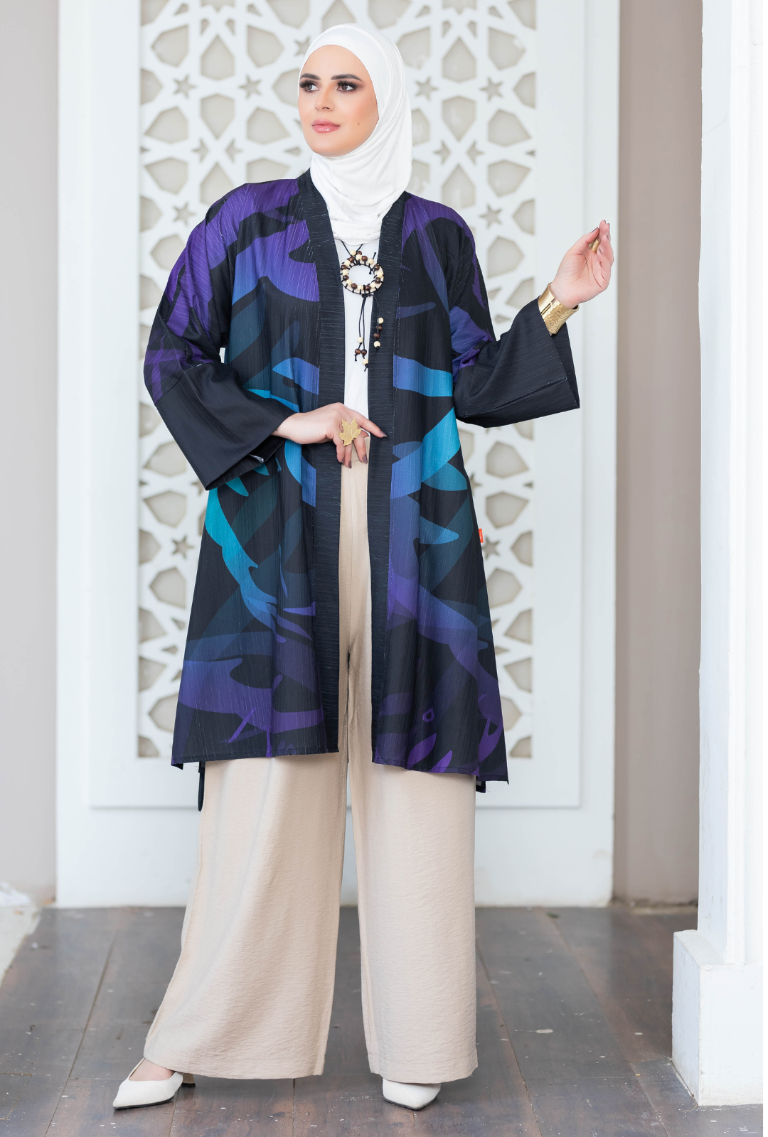 Vibrant digital-printed kimono with intricate geometric patterns in shades of blue, purple, and black, worn over beige palazzo pants.