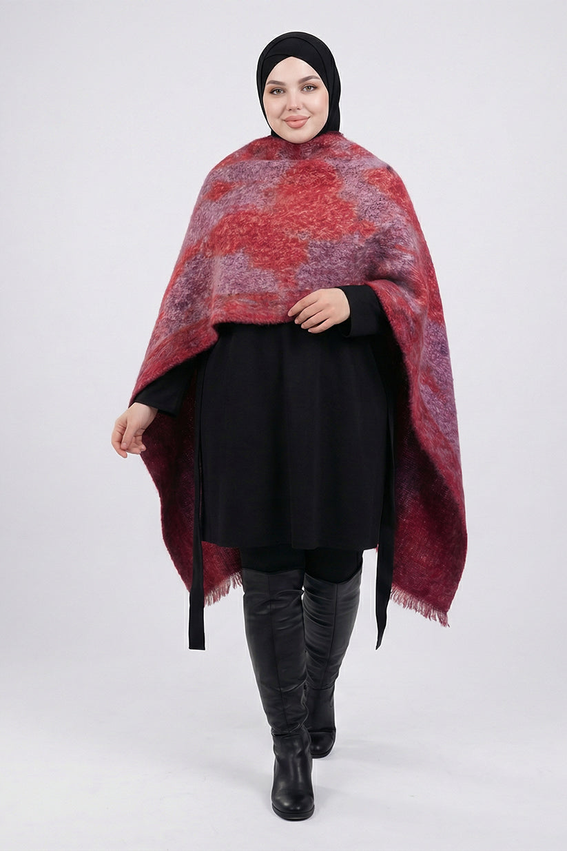 Woman wearing a red patterned poncho over a black outfit on a white background