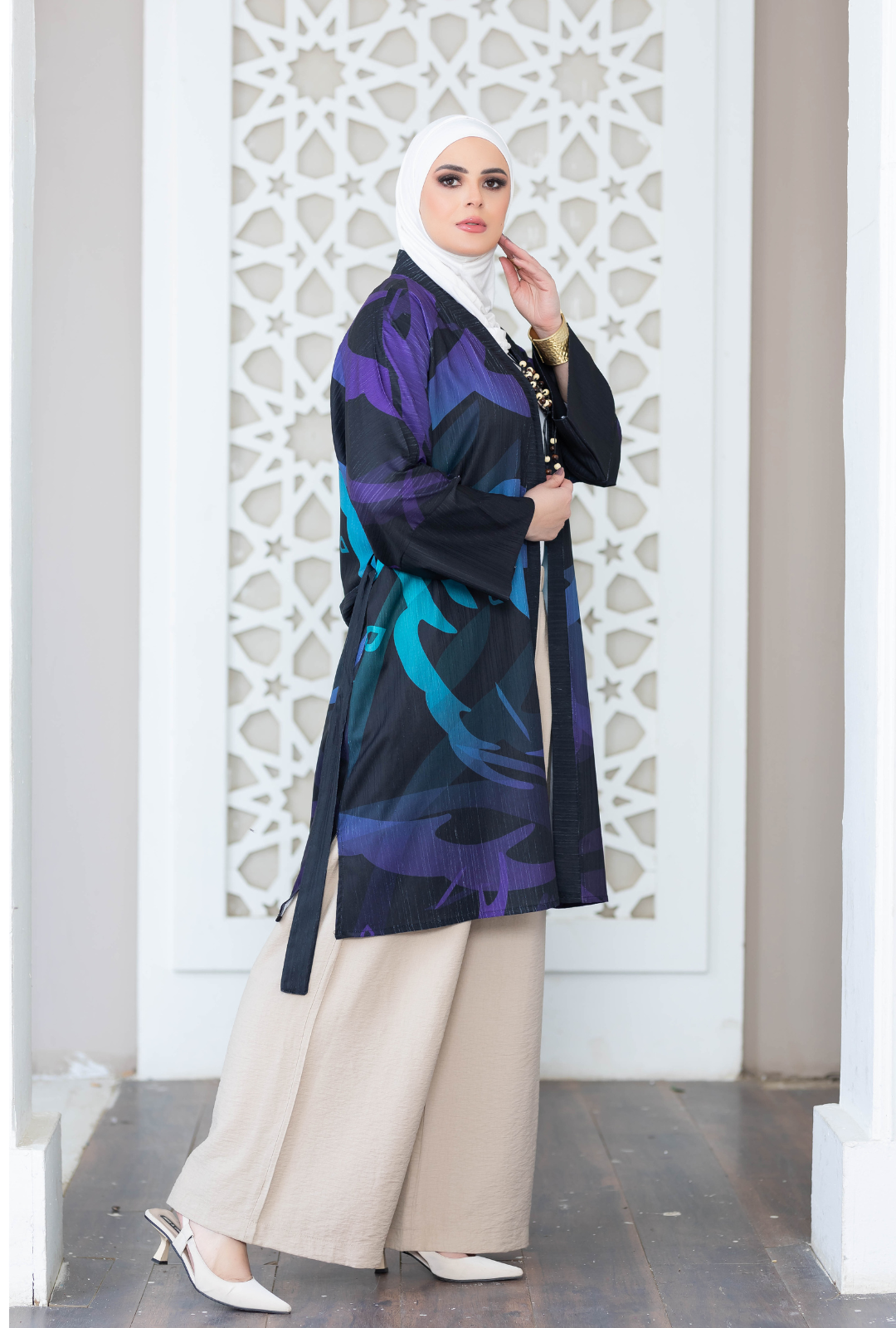 Digital print kimono with vibrant purple, teal, and black colors displayed against a white architectural background.