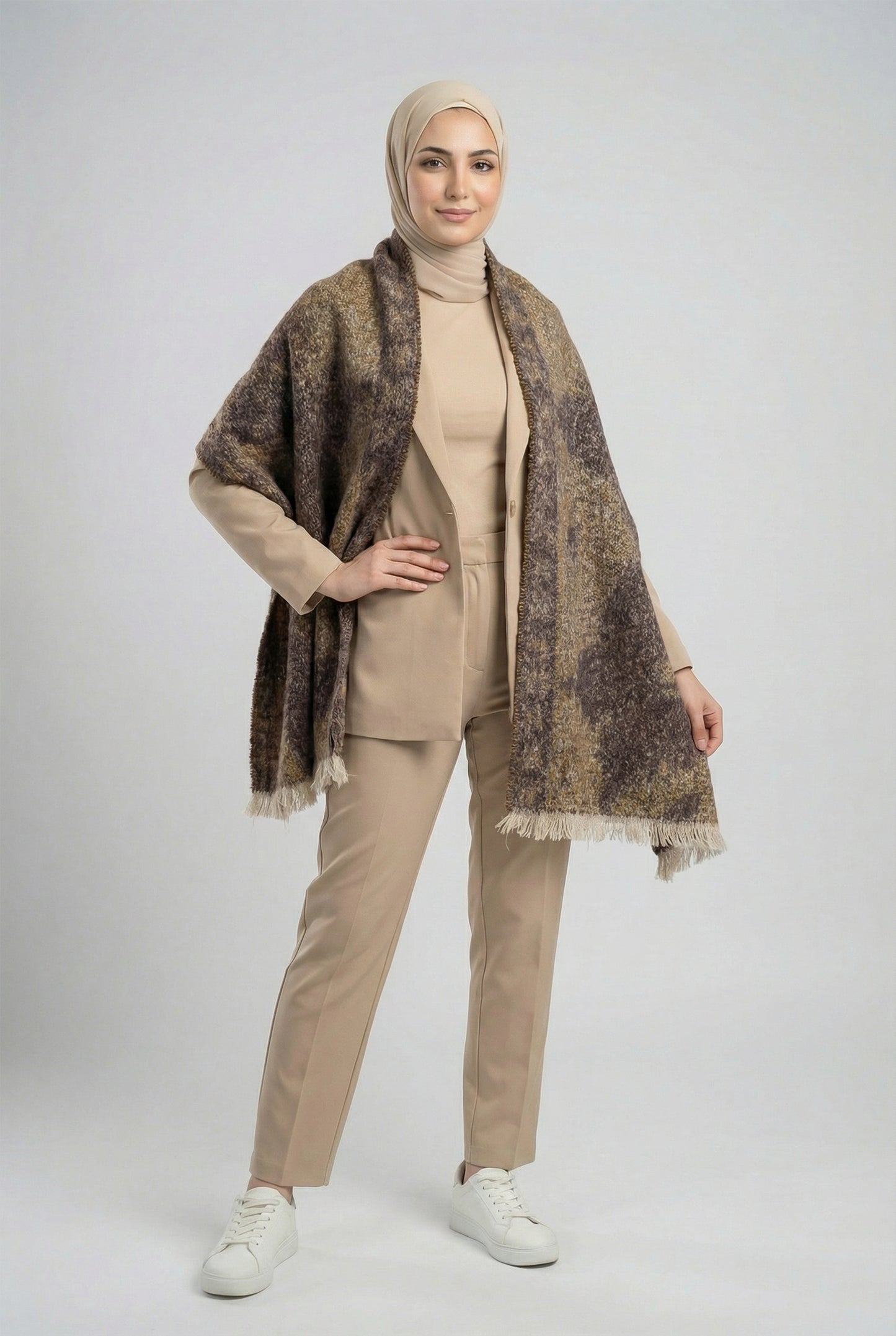 Woman wearing a beige outfit with a patterned shawl on a white background
