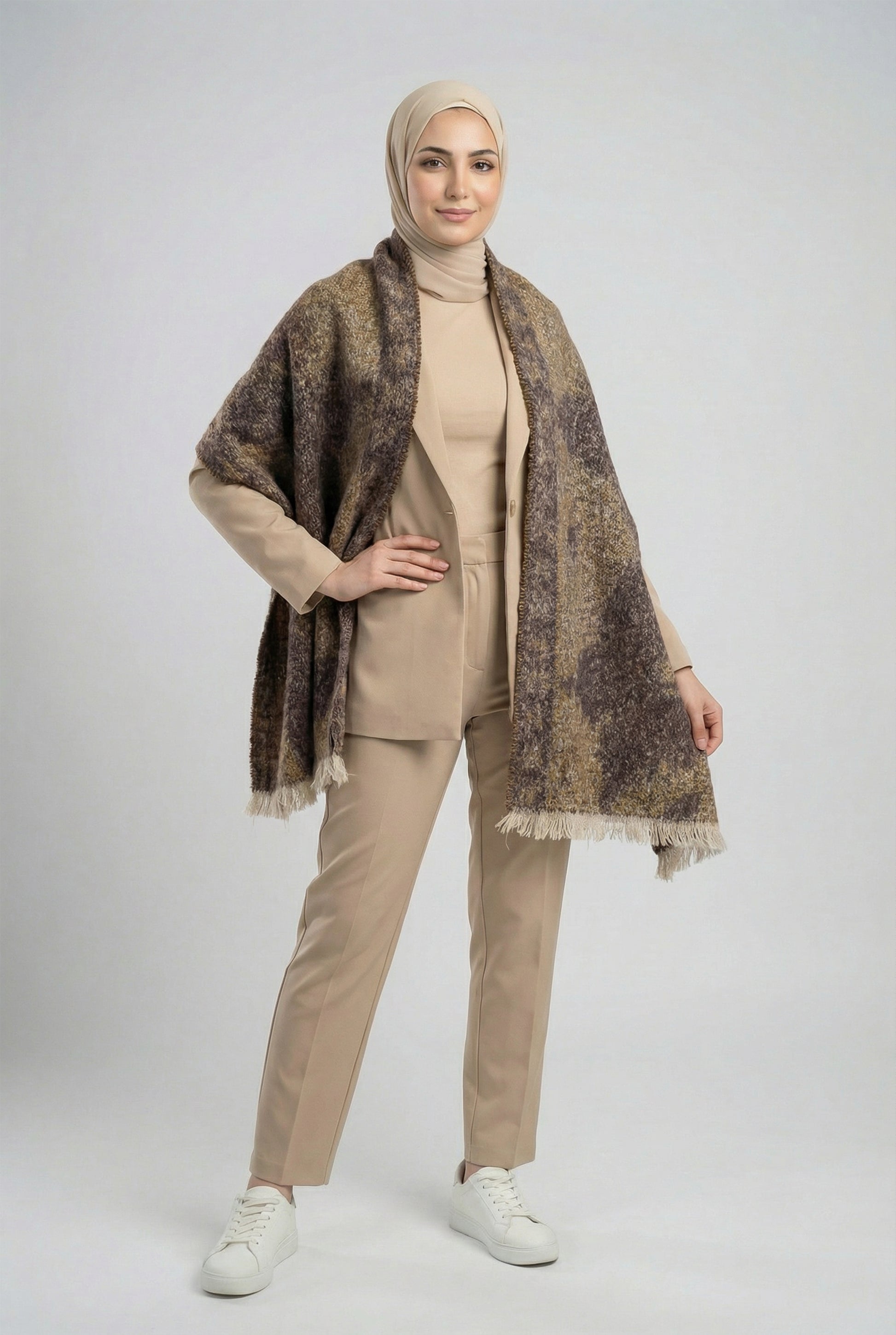 Woman wearing a beige outfit with a patterned shawl on a white background
