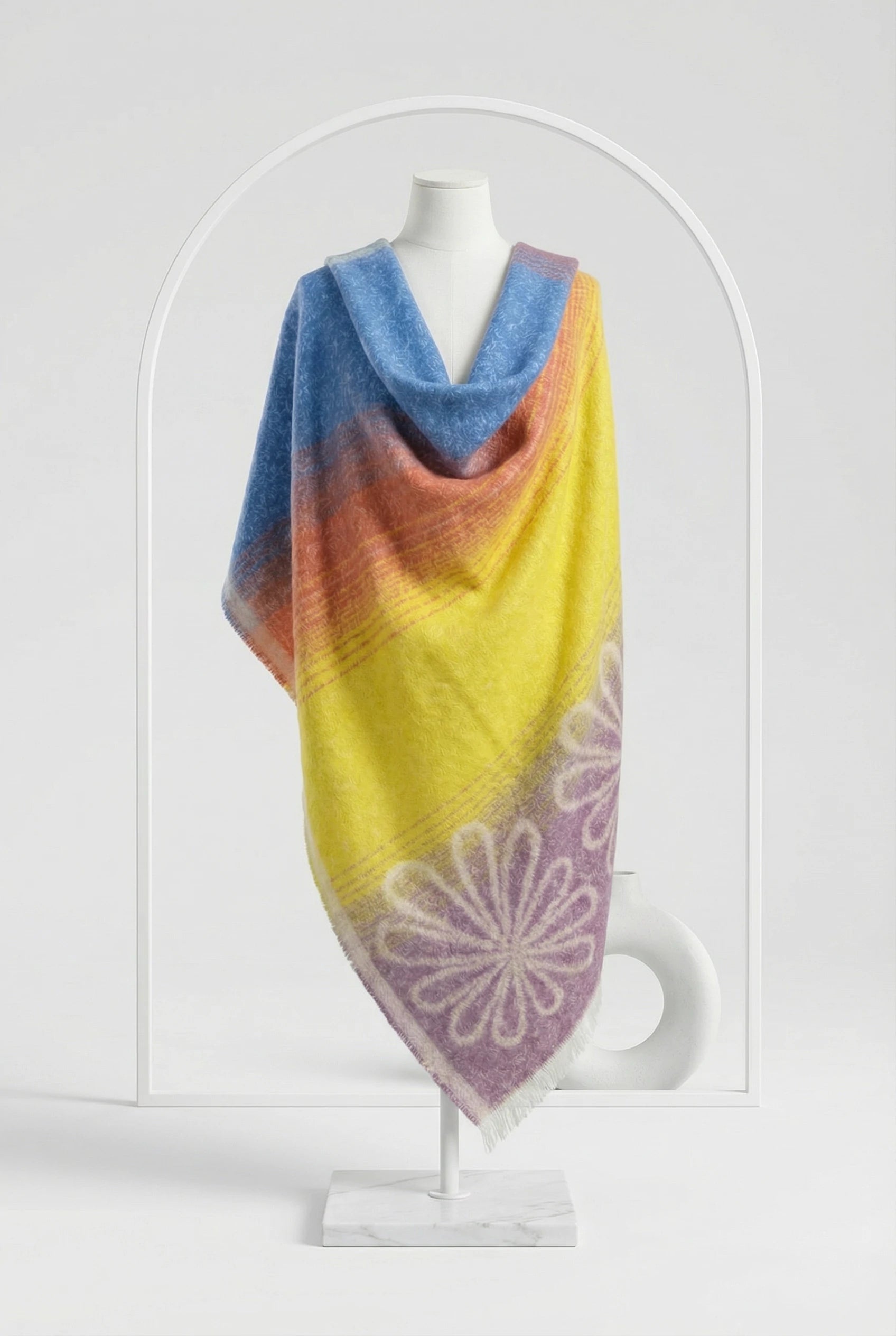 Colorful knitted shawl with a floral pattern on a mannequin against a white background