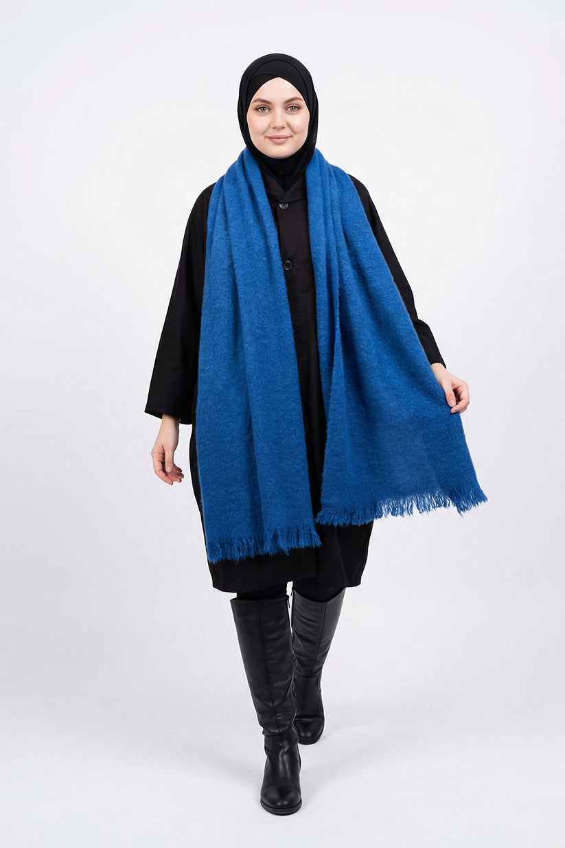 Person wearing a blue scarf, black outfit, and black hijab on a white background