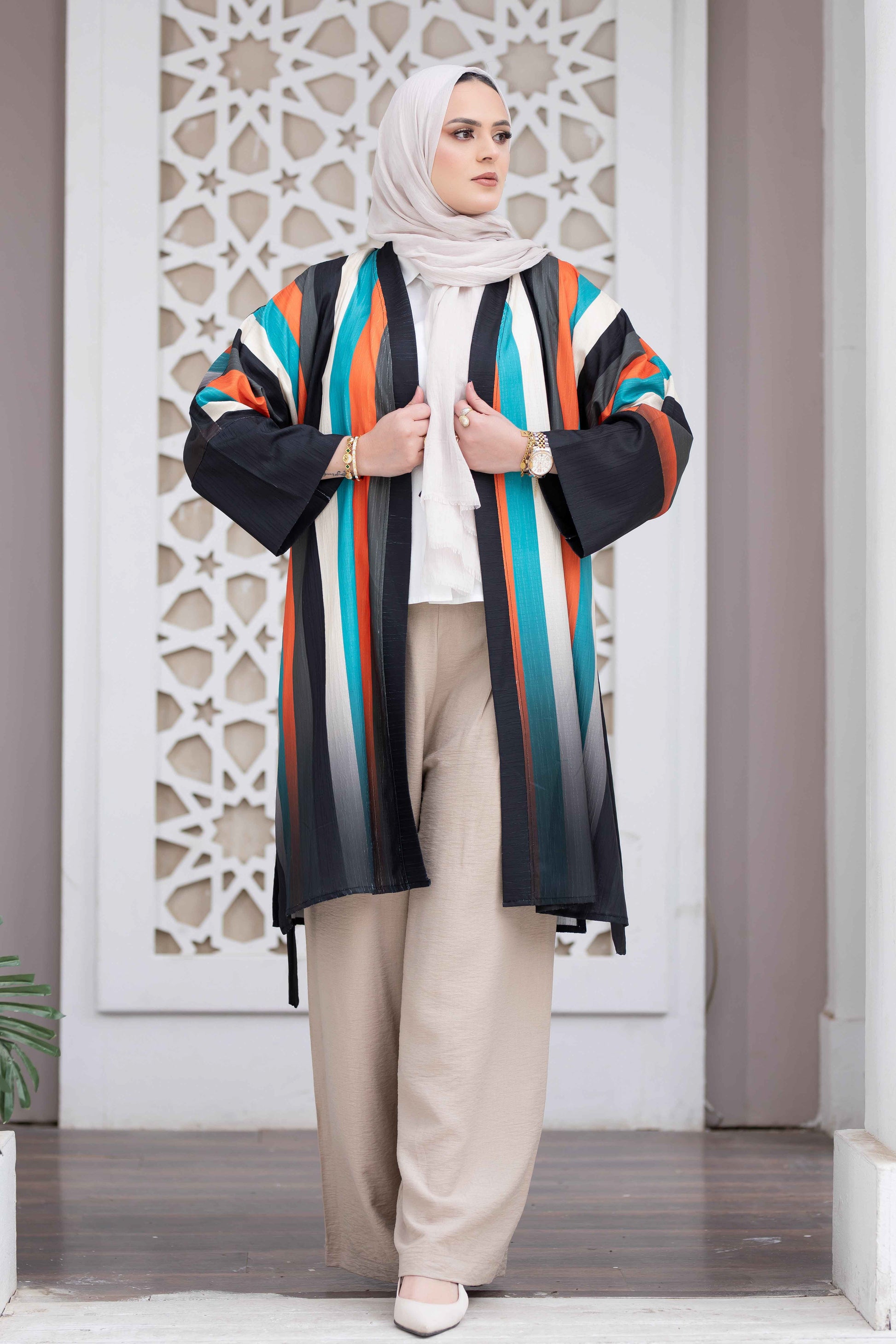 Colorful striped open kimono, modest woman's fashion, Islamic-inspired architectural background