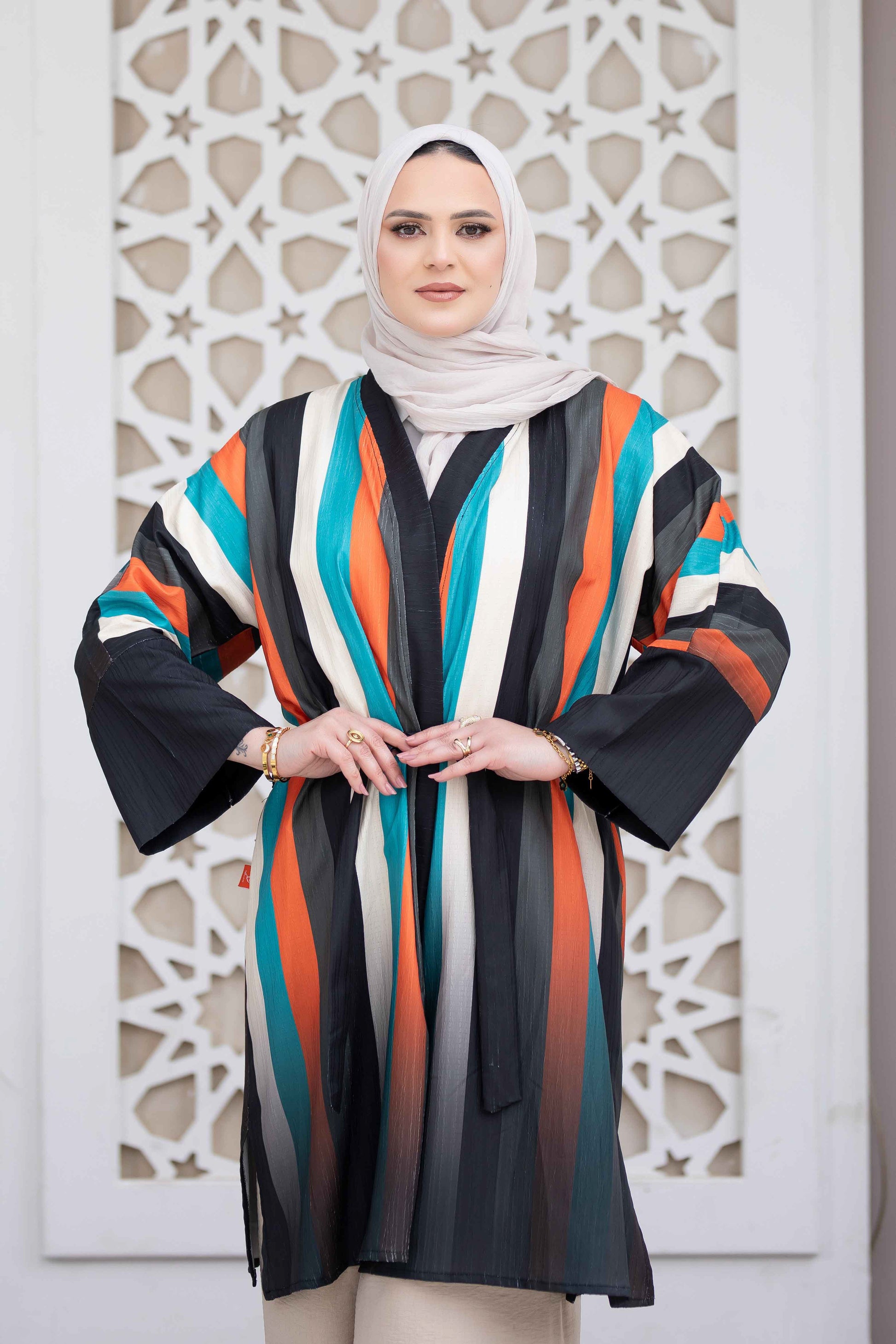 Colorful long striped kimono dress with graceful woman wearing hijab against intricate architectural background