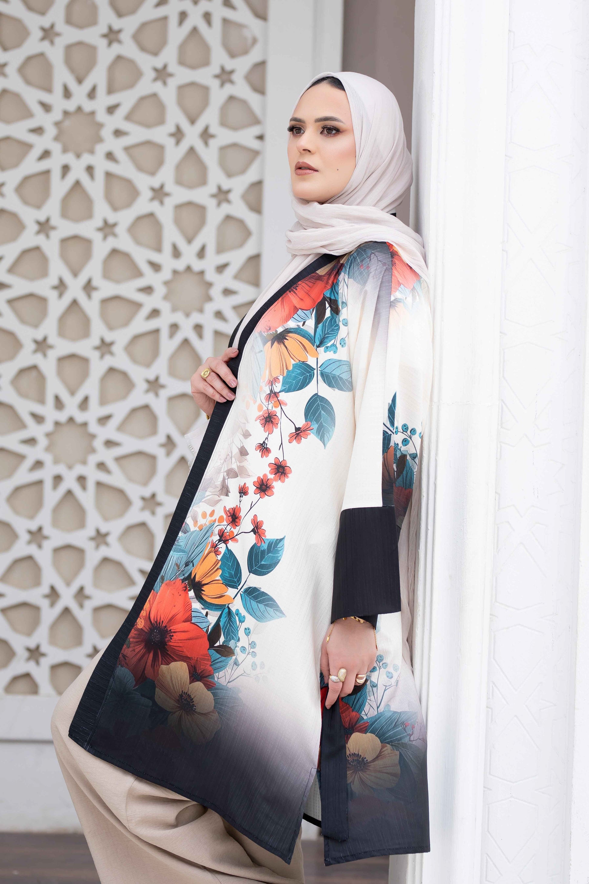 Elegant floral kimono with vibrant blooms against a white backdrop, stylishly worn with a hijab.