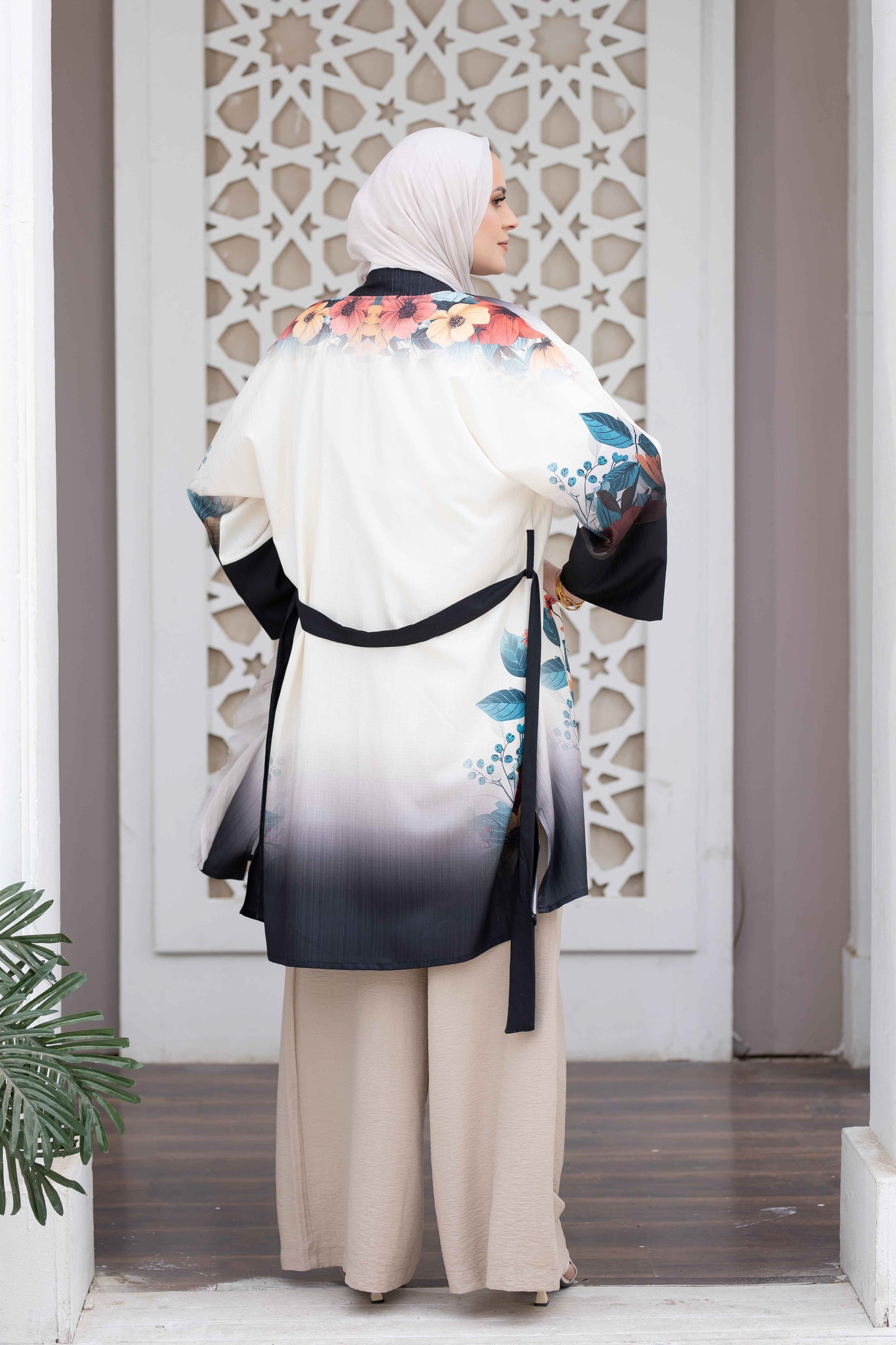 Elegant printed kimono with colorful floral patterns and flowing sleeves, worn by a woman standing in front of an ornate architectural backdrop.